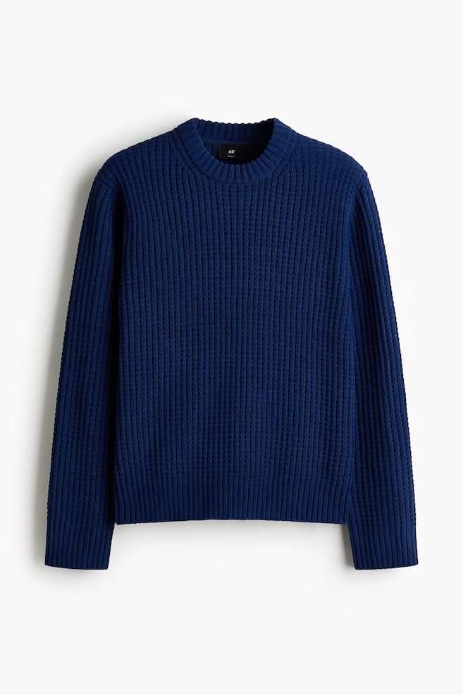 A dark blue jumper is presented from the FRONT, featuring a chunky vertical ribbed knit throughout its body and long sleeves, while also displaying a crew neck and ribbed cuffs and hem. - 1