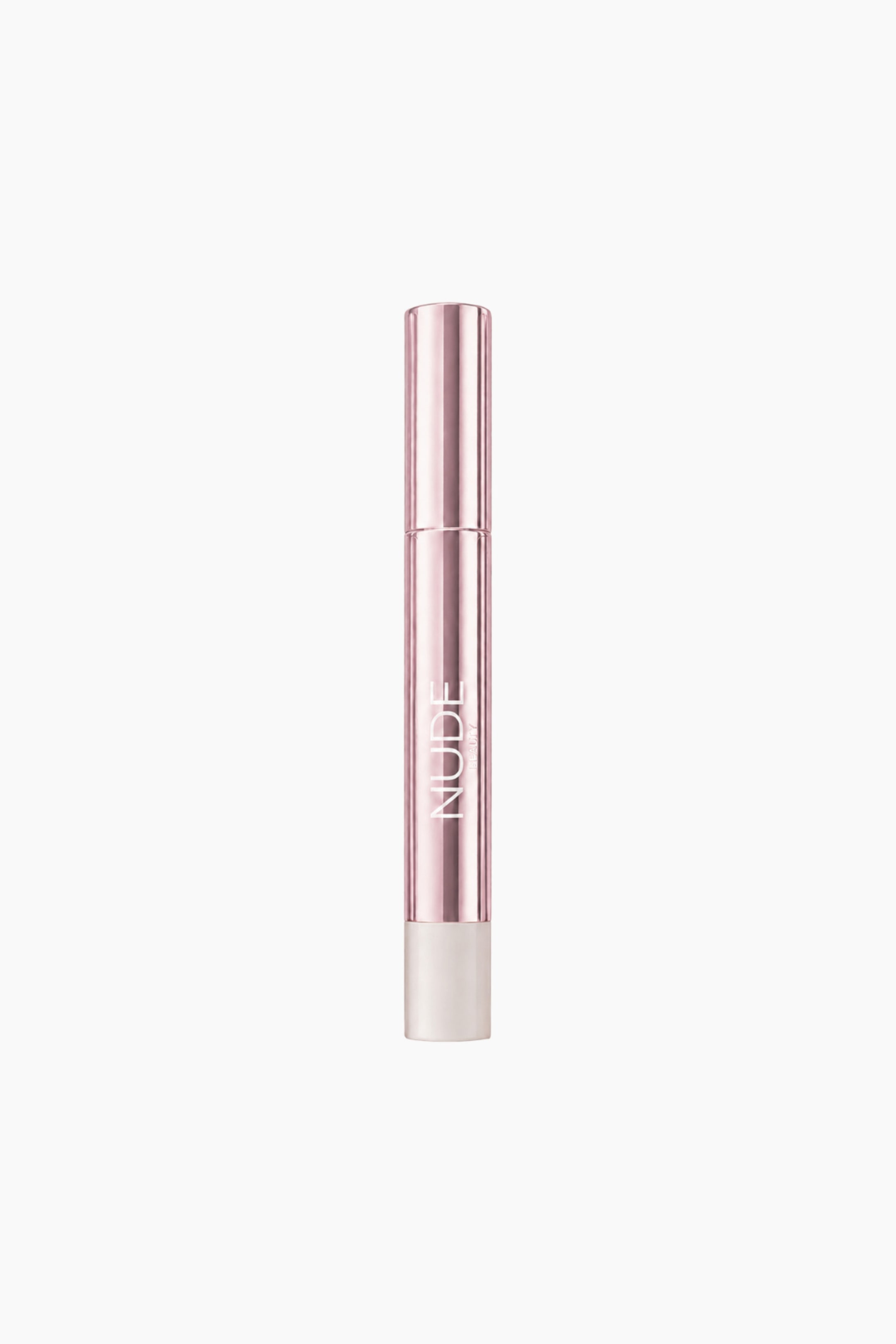 Vis større bilde: En sylindrisk kosmetisk stick står oppreist, med en blank roségullkropp med "NUDE" trykt loddrett på den, og en matt hvit base.