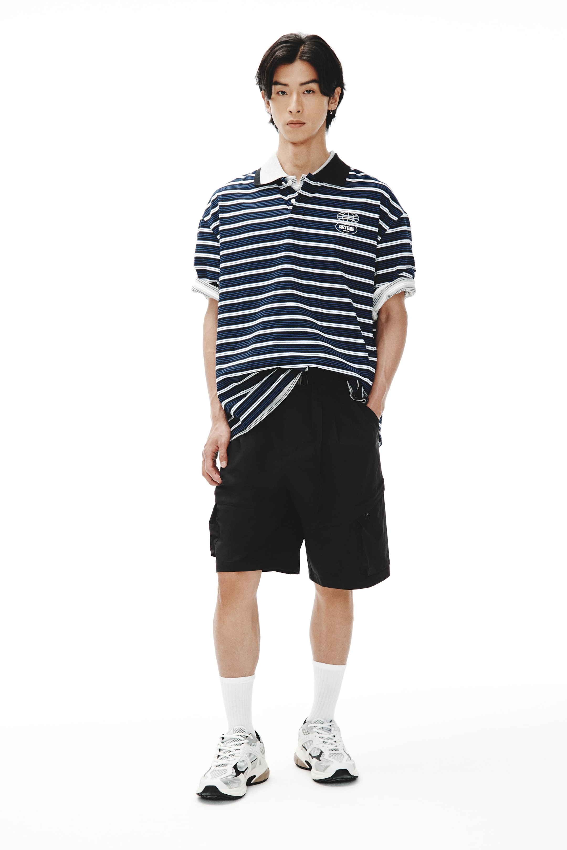 View larger image: The model is wearing a navy blue, white, and light blue striped polo shirt. It has a black top collar, a white undercollar, and rolled short sleeves. There's an embroidered logo on the chest. The model is layering it over a white t-shirt, which is visible at the hem and sleeve cuffs.