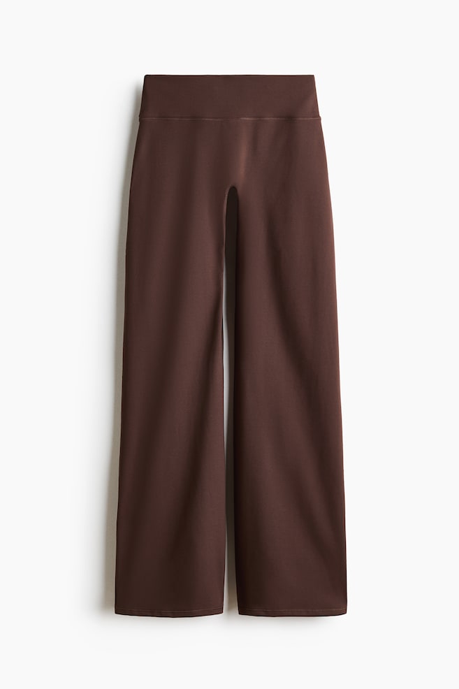 Wide brown sports trousers are laid flat, front-facing, featuring a high-rise, wide waistband and wide legs with a smooth fabric texture and straight hems. - 1