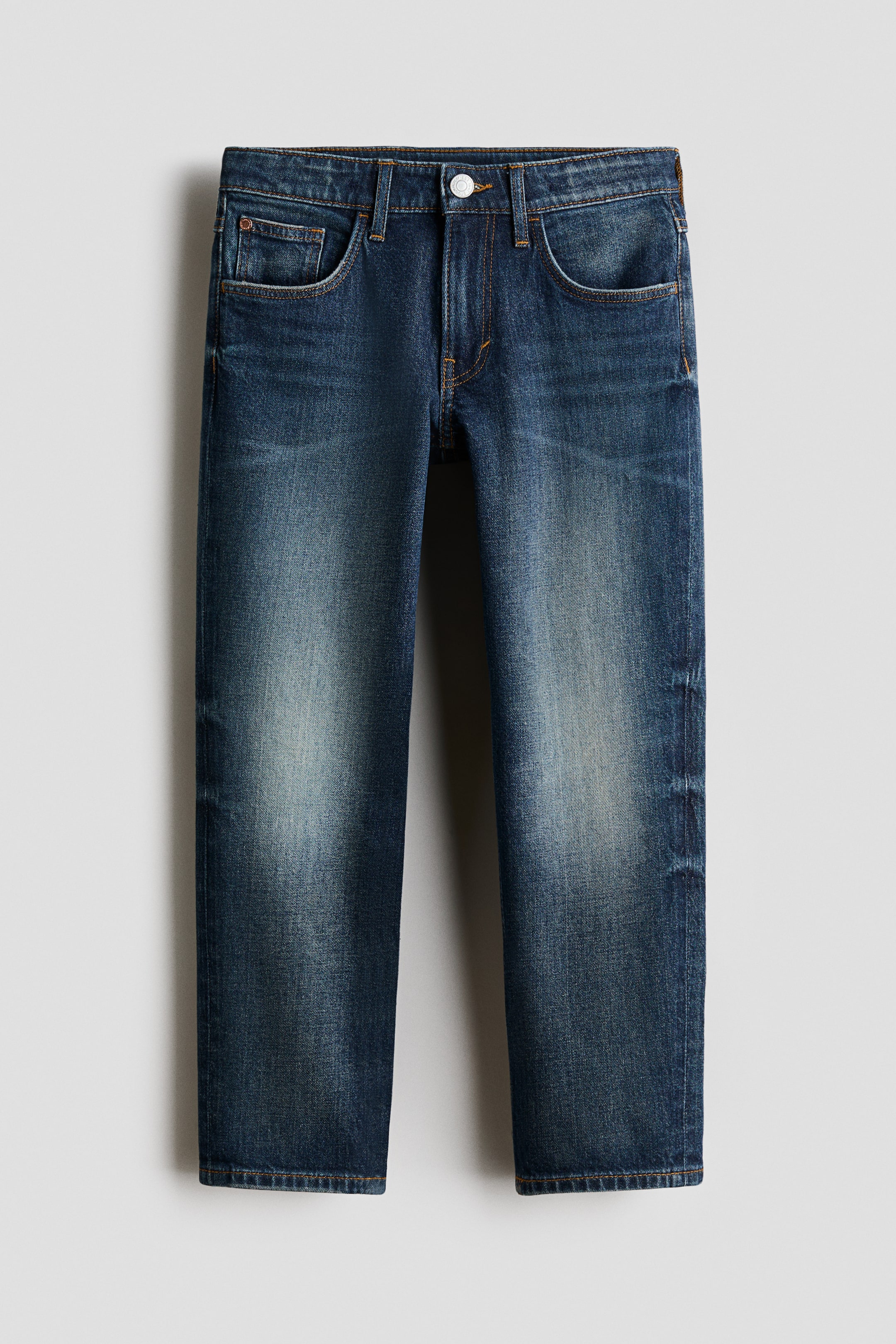 View larger image: A pair of blue denim jeans is facing front, showcasing a washed finish with lighter fading on the thighs and knees. It features a relaxed fit, two front pockets, a coin pocket, a button and fly closure, and tapering legs.