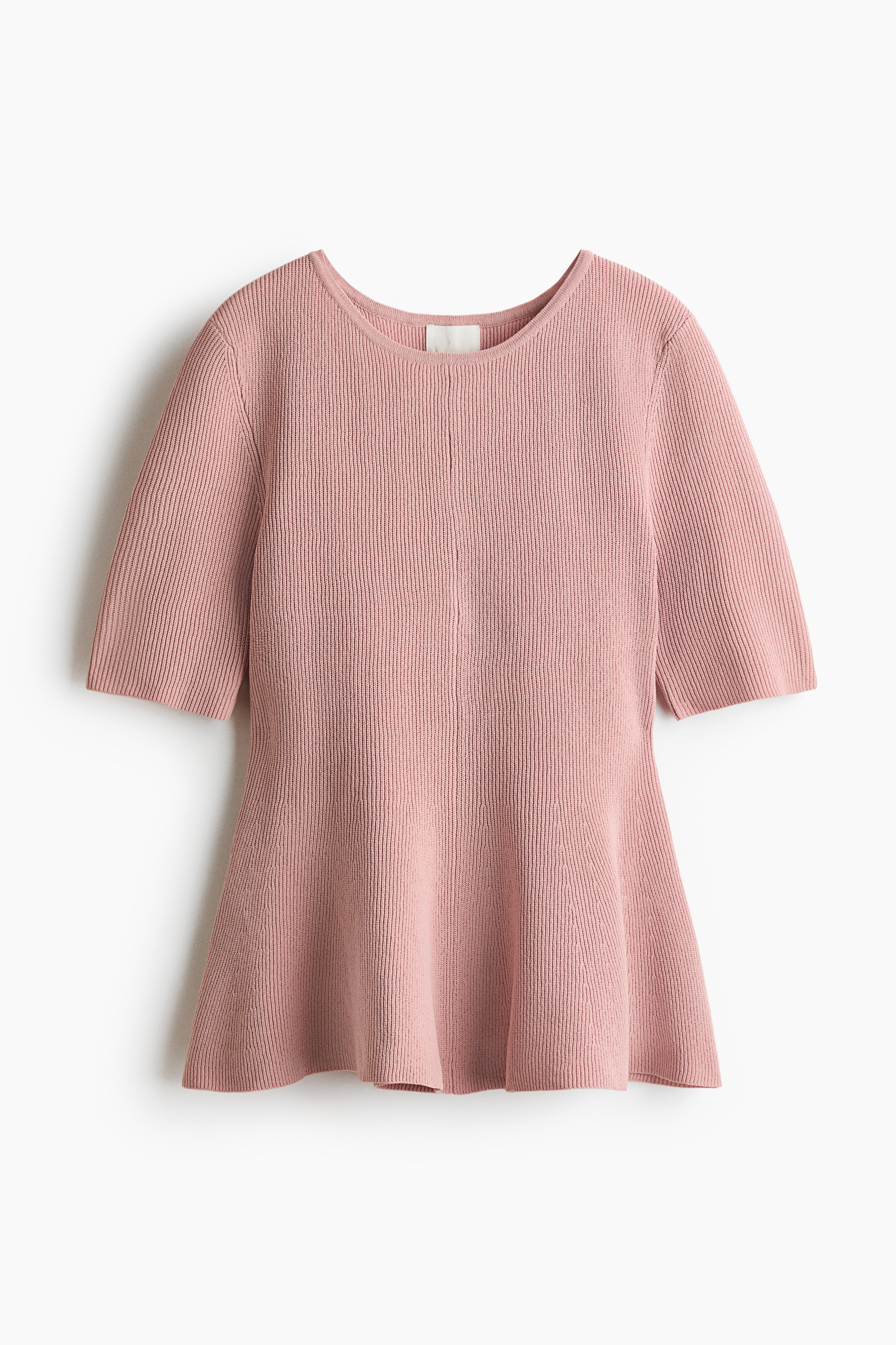 The model is wearing a pink knit top featuring a round neckline, elbow-length sleeves, and a flared peplum hem. The top is styled with wide-leg blue jeans.