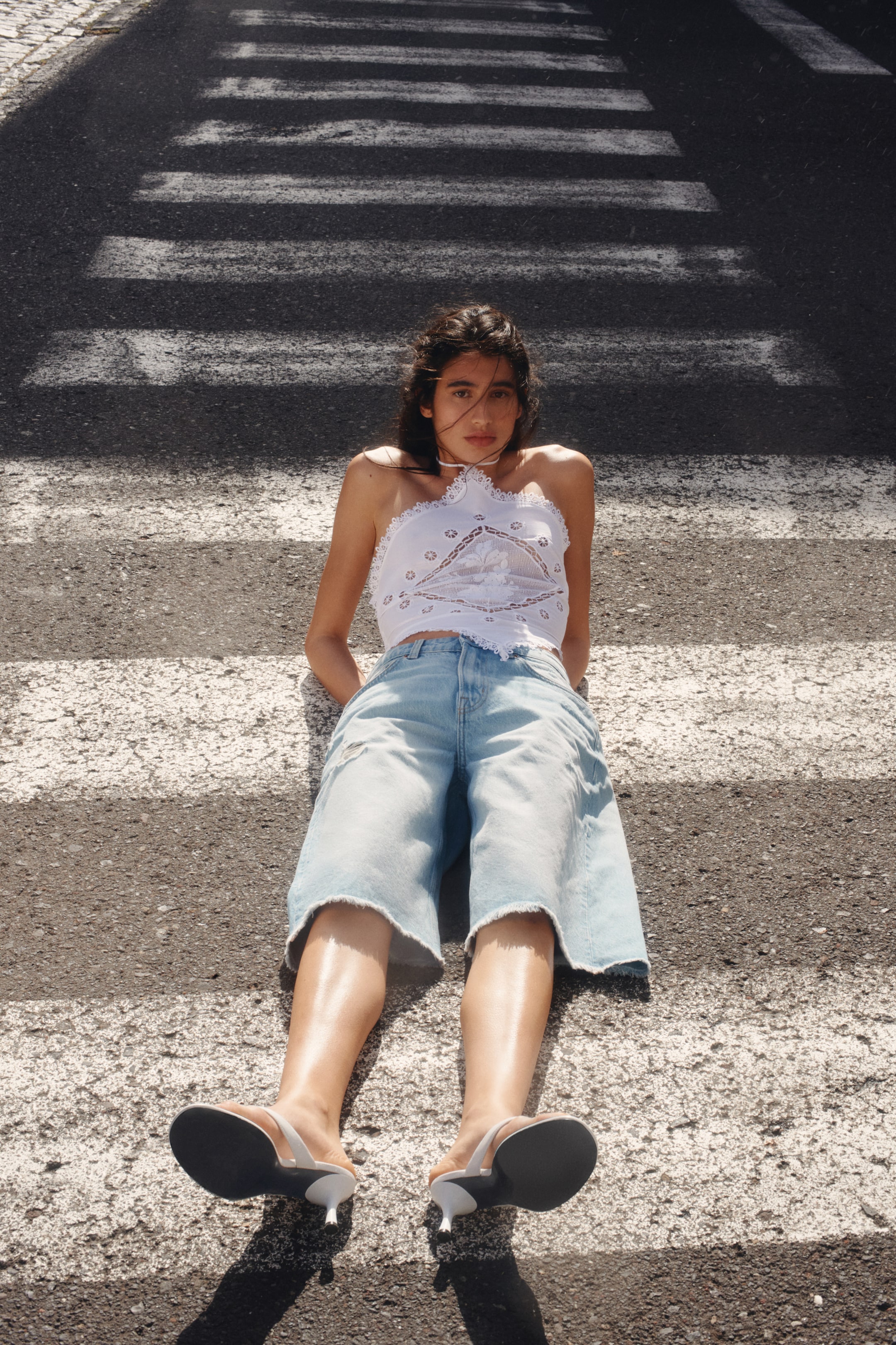 View larger image: This white halter neck top showcases intricate lace detailing and embroidery on its front panel, designed with a scalloped lace trim along the neckline, armholes, and cropped hem.