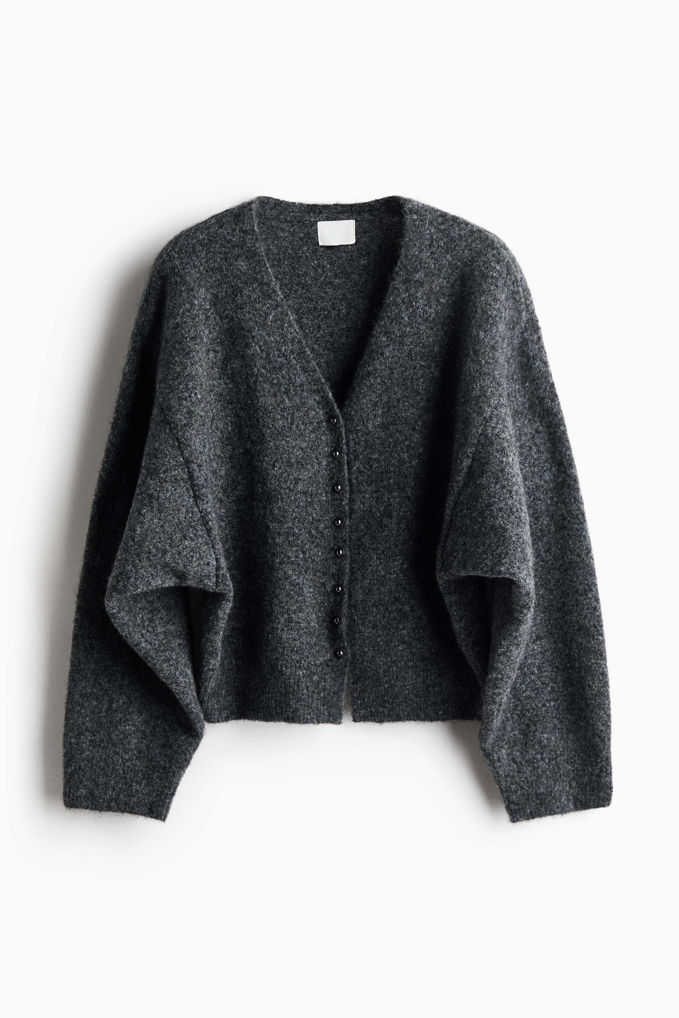 Größeres Bild anzeigen: Eine dunkelgraue, flauschige Strickjacke ist frontal zu sehen und verfügt über einen tiefen V-Ausschnitt sowie einen vorderen Verschluss mit kleinen, dunklen Knöpfen. Die Strickjacke zeigt eine oversized, entspannte Silhouette mit weiten, lässig fallenden Ärmeln und gerippten Bündchen an den Ärmelabschlüssen und am Saum.