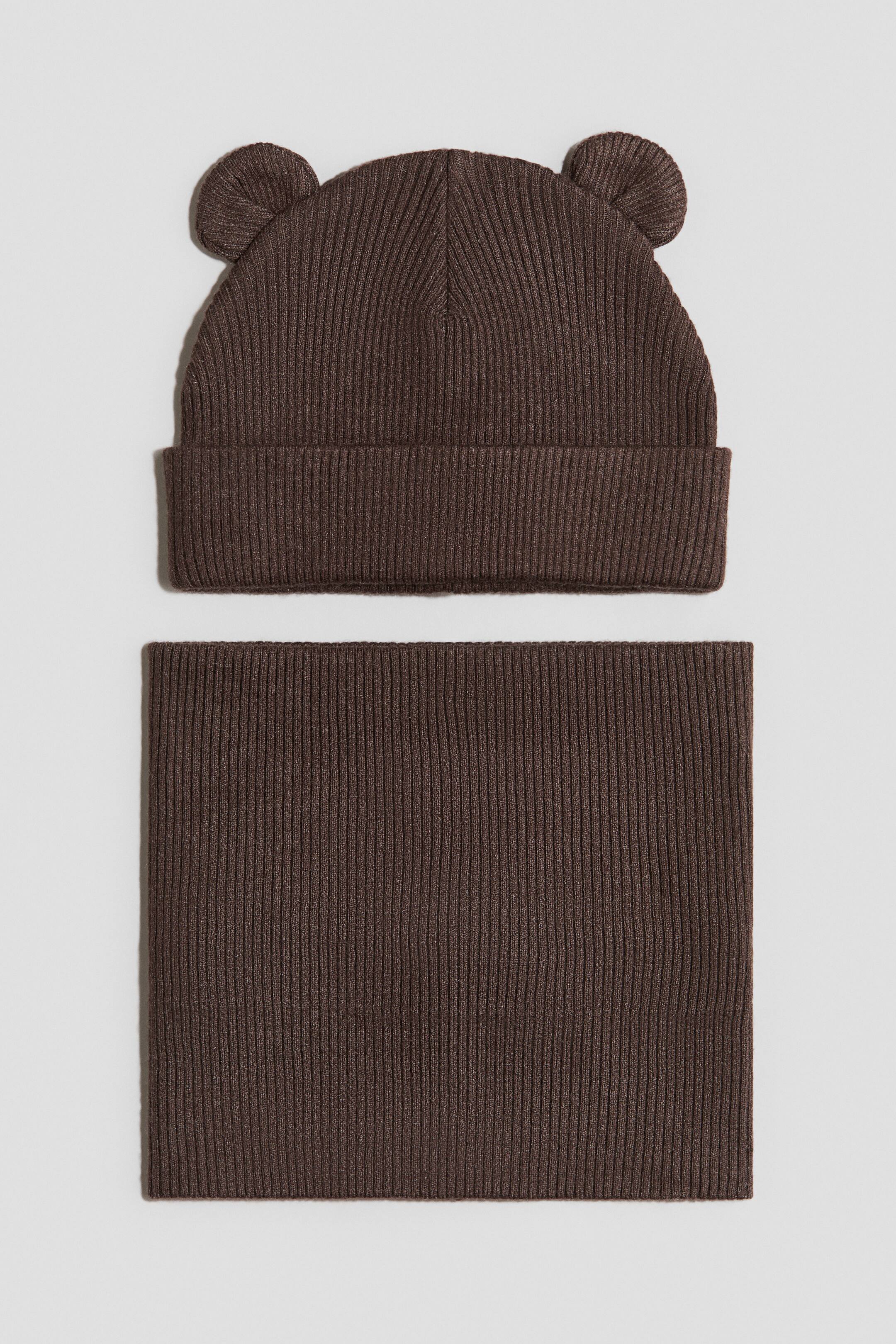 View larger image: A brown ribbed knit beanie and a matching rectangular ribbed knit neck warmer are laid flat, facing front. The beanie features two small, rounded ear-like protrusions on top and a folded brim.