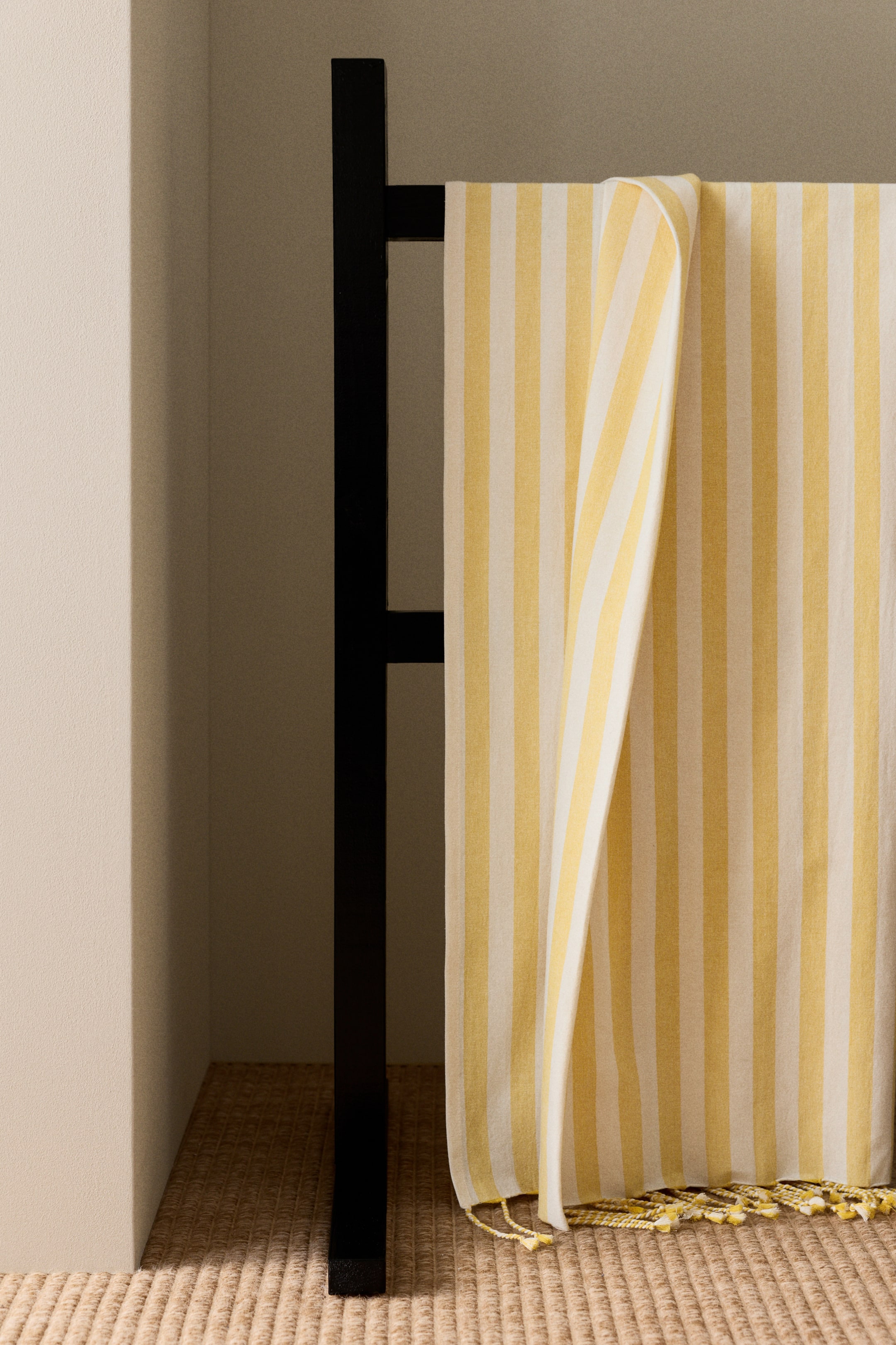 View larger image: A large beach towel is draped, showcasing a yellow and white striped pattern in a cotton weave. Twisted fringes are visible along its bottom edge.