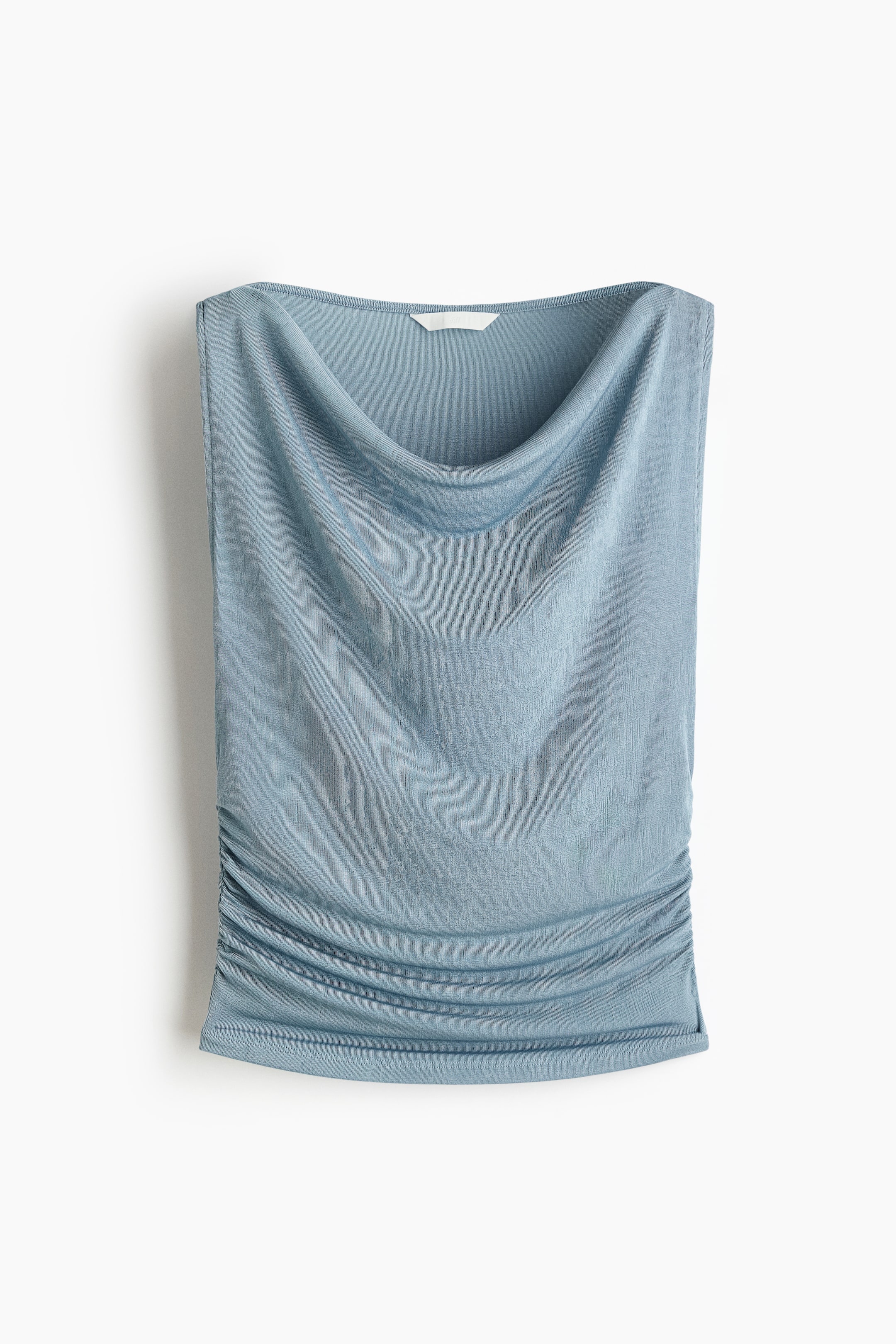 Ver imagen más grande: Un top sin mangas de color azul claro se presenta de frente, con un escote drapeado en forma de cowl. La tela del top muestra una sutil textura arrugada, y su lado inferior derecho se recoge en un suave fruncido.