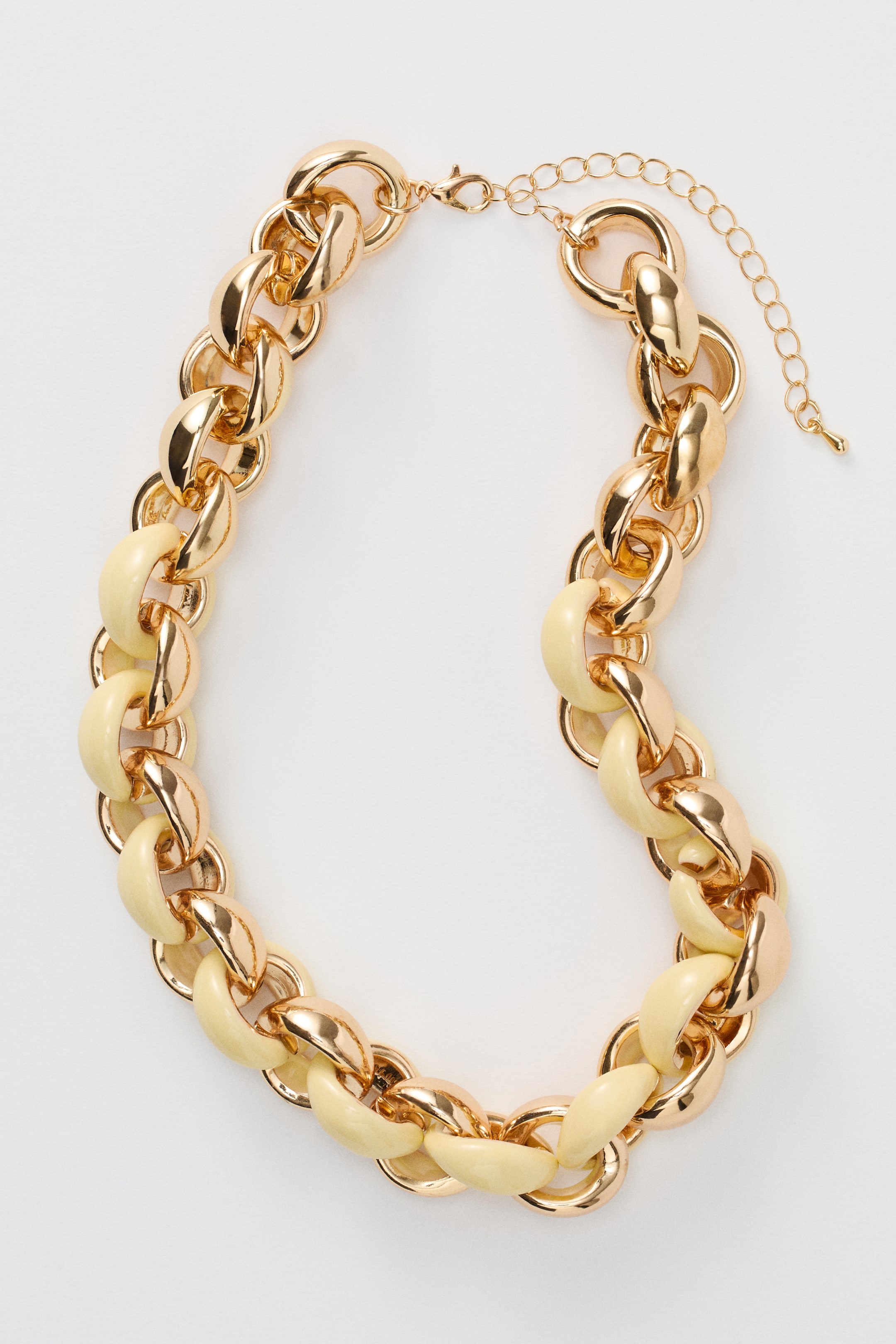 Grösseres Bild ansehen: Eine Halskette aus einer massiven goldfarbenen Metallkette, die vorne mit hellgelben Gliedern versehen ist. Sie bietet eine verstellbare Länge und wird mit einem Karabinerverschluss gesichert.