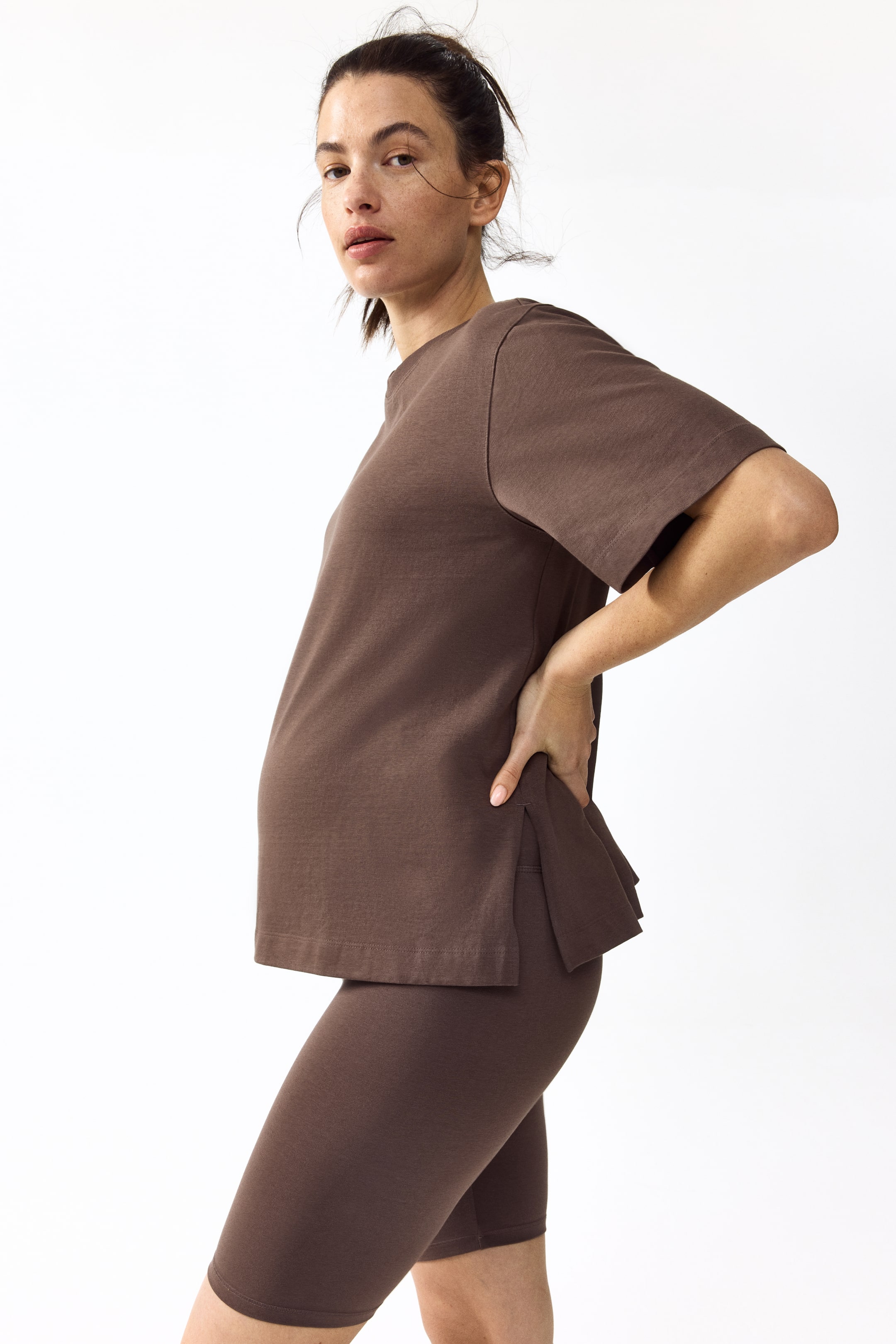 View larger image: A brown two-piece set, featuring a short-sleeve t-shirt and mid-thigh bike shorts, is showcased from a side-back angle. The t-shirt displays a relaxed fit, a crew neck, and side slits at the hem, while the fitted shorts reach mid-thigh.