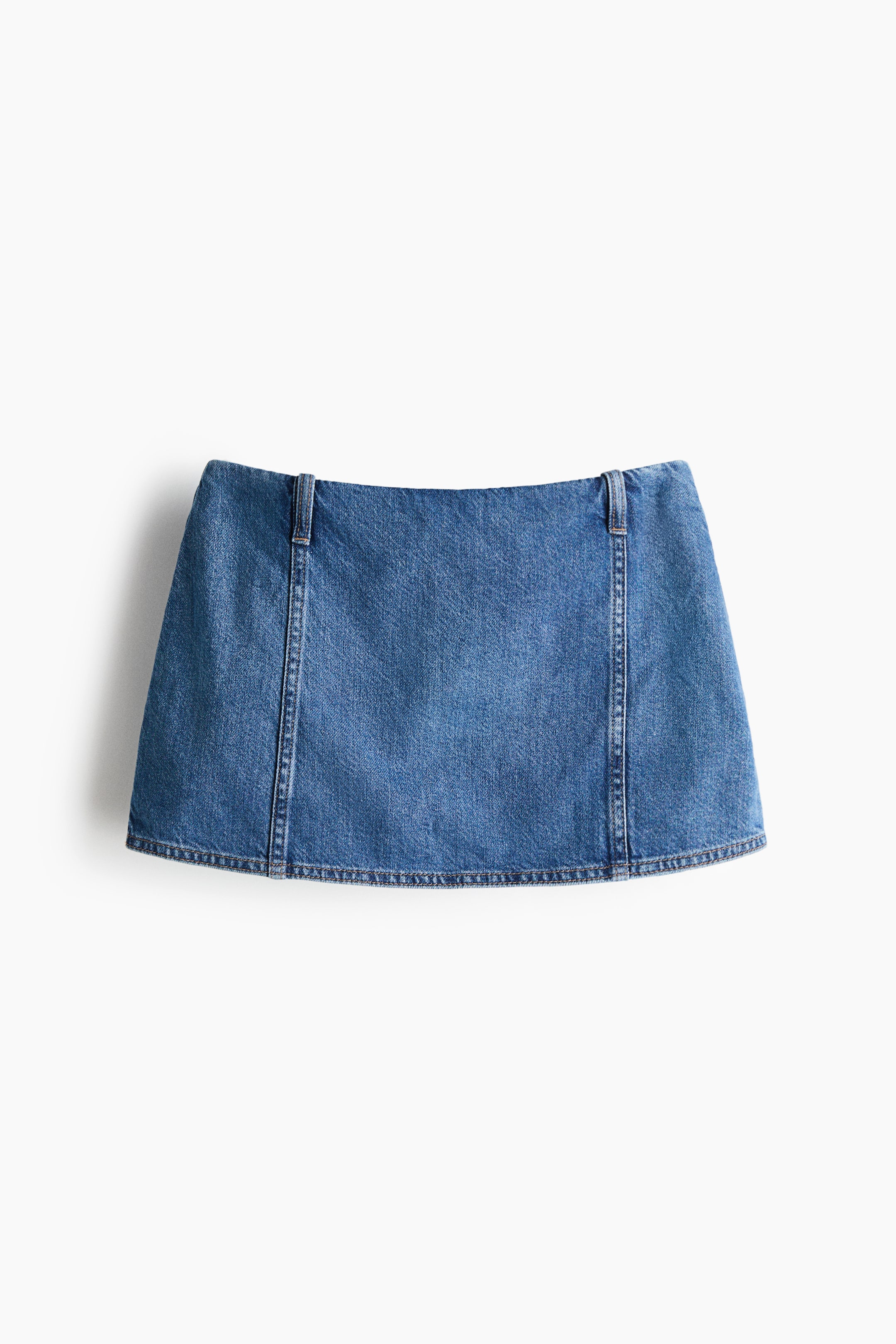 View larger image: A blue denim mini skirt is shown from the front, featuring a flat waistband with two belt loops at the top sides. Vertical seams run down the front, and a double-stitched hem is visible along the bottom edge.