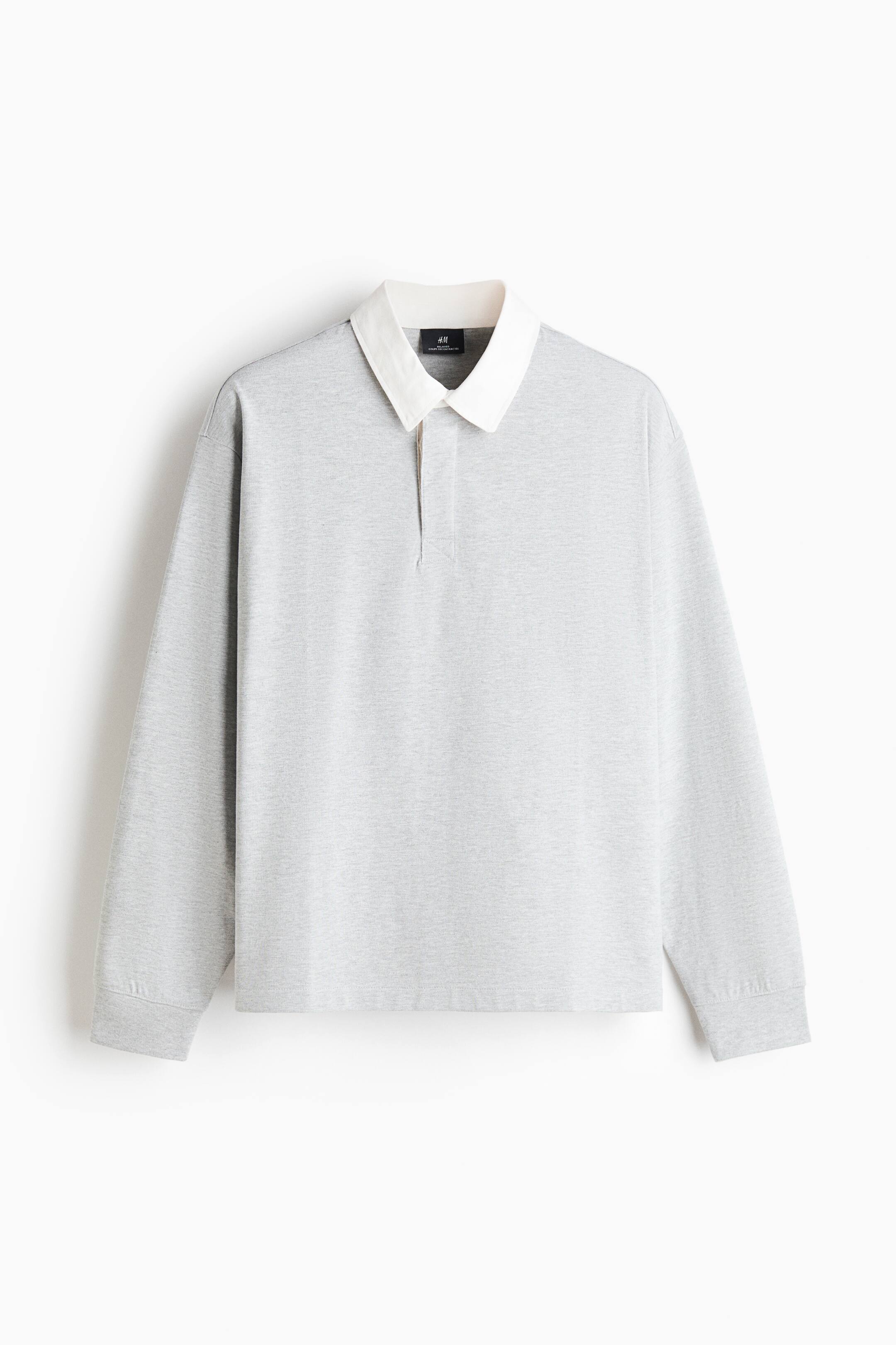 View larger image: A light gray heathered long-sleeve polo shirt is shown from the front, featuring a contrasting off-white collar and a clean, buttonless placket. The shirt has dropped shoulders, ribbed cuffs, and a straight hem.