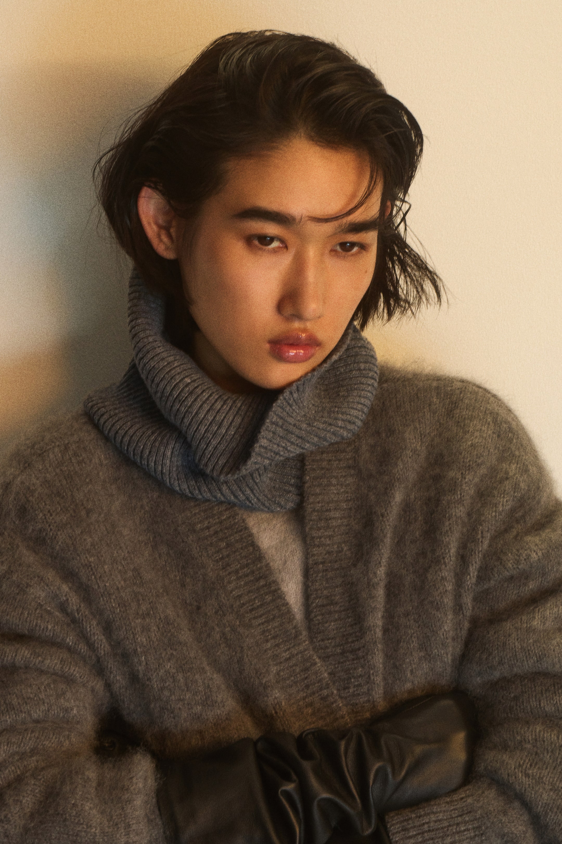 Ver imagen más grande: Una bufanda tubular de punto canalé en un suave color azul grisáceo está puesta alrededor del cuello de la modelo. Va superpuesta por debajo de un cárdigan de punto gris con textura afelpada.