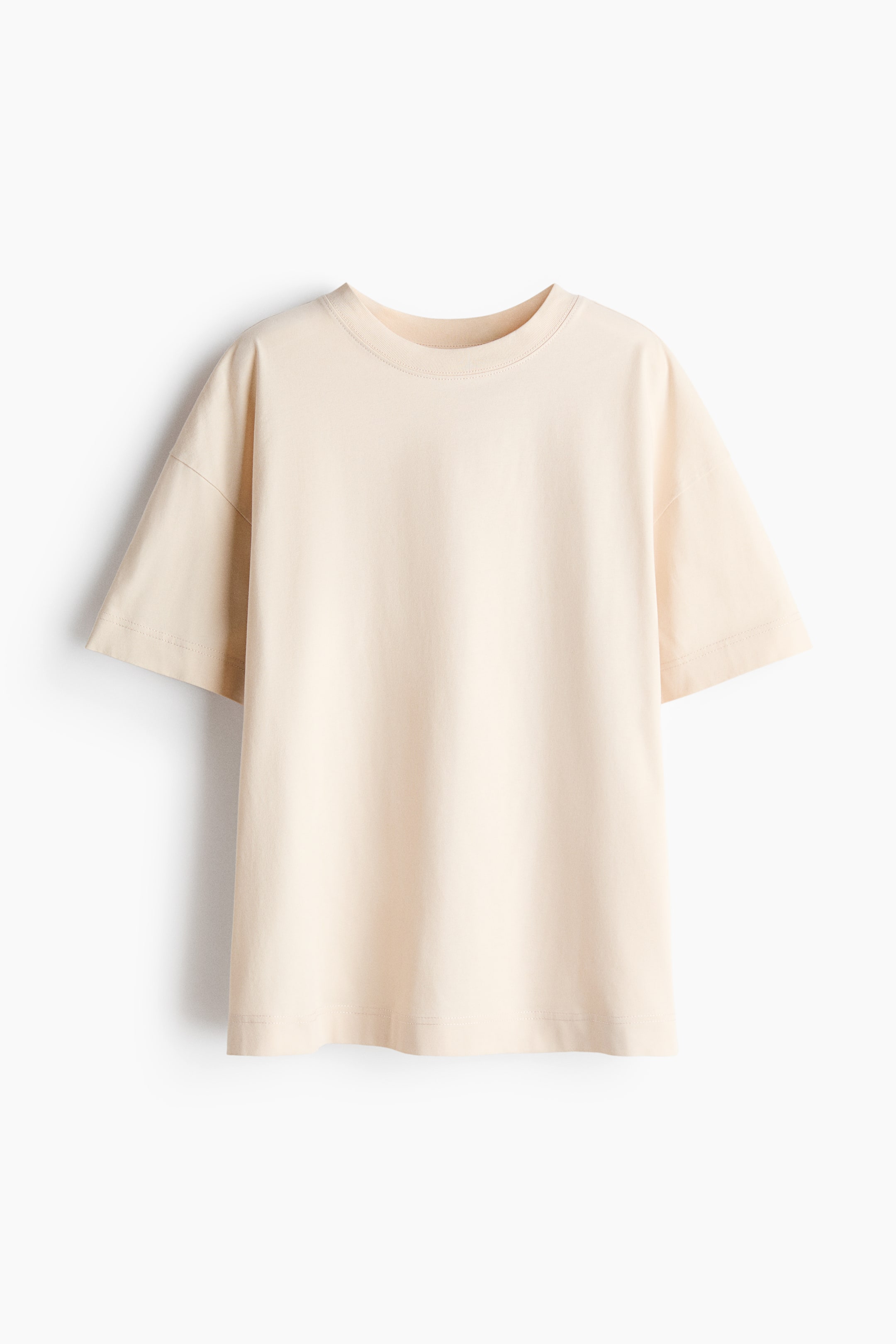 Ver imagem maior: A T-shirt oversized em jersey de algodão creme claro é apresentada de frente, exibindo uma gola com acabamento em canelado, ombros descaídos e uma bainha de corte reto.