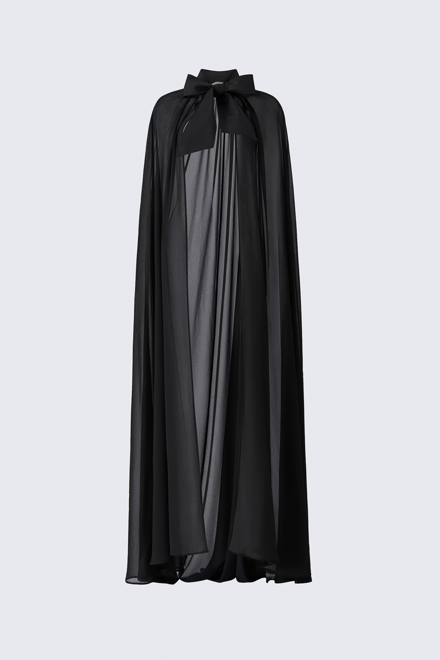 A floor-sweeping black cape crafted from a sheer weave is draped in a front-facing view. It features a high collar adorned with a large, double-layered bow at the neck, with gathers along the collar stand creating a voluminous, flowing silhouette.