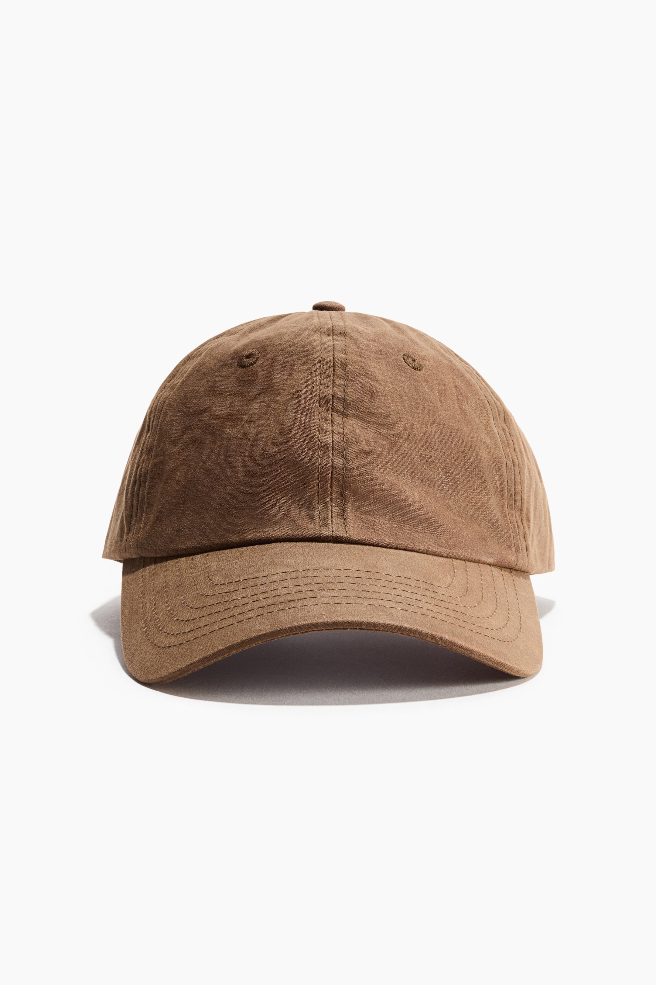 View larger image: A brown baseball cap is facing front, showing a soft crown with two visible ventilation eyelets and a matching fabric-covered top button. Its curved brim features multiple rows of parallel stitching.