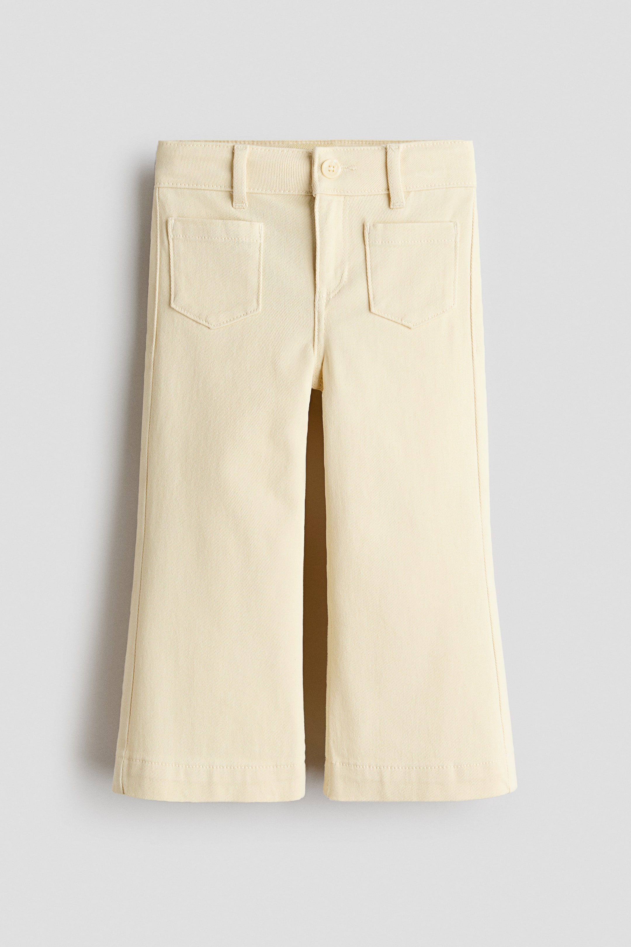 Visualizza immagine più grande: Pantaloni alla caviglia in twill di cotone giallo chiaro presentati frontalmente, caratterizzati da una vestibilità regolare su fianchi e cosce con gambe svasate, chiusura con zip e bottone, e due tasche applicate sul davanti.