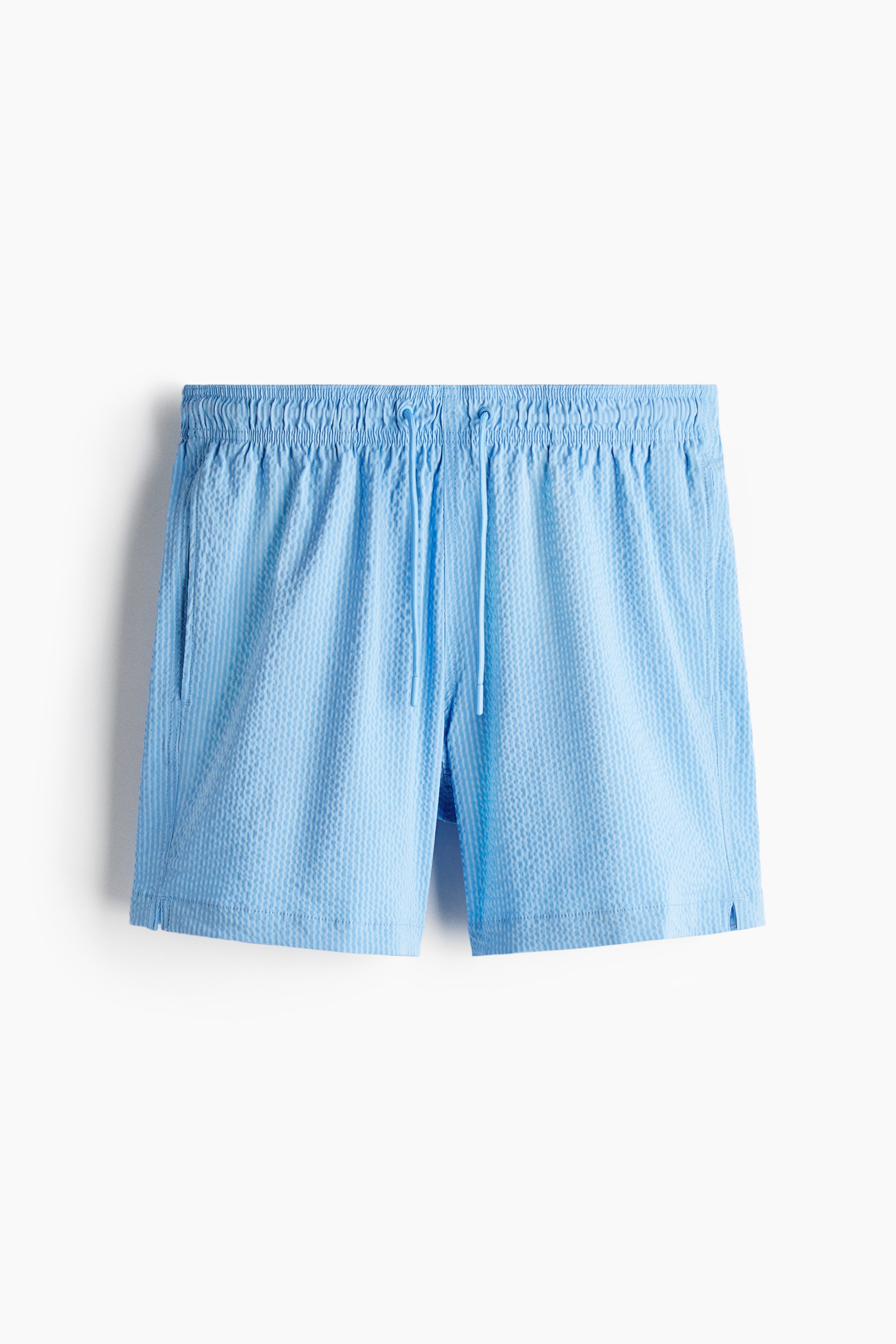 View larger image: Light blue seersucker shorts are presenting flat, facing forward. They feature an elasticized waistband with a visible drawstring, vertical side pockets, and small slits at the outer leg openings.
