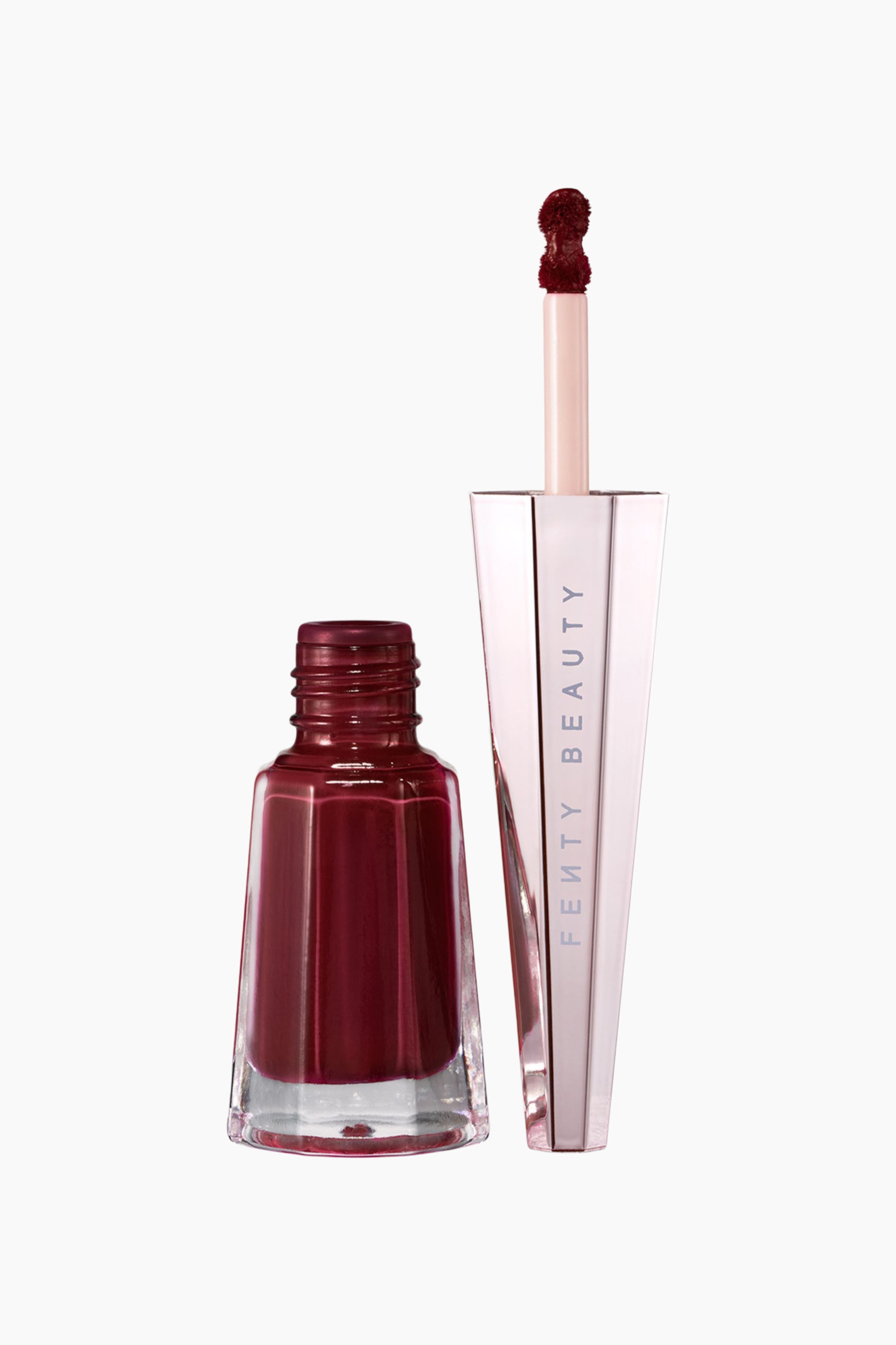 Visa större bild: Stunna Lip Paint Longwear Fluid Lip Color visas som en öppen, facetterad glasflaska fylld med en djupt burgundyfärgad flytande formula bredvid dess geometriska lock i roséguldsnyans. Locket står upprätt och exponerar en tillhörande applikatorstav med produkten i matchande plommonfärg i spetsen.