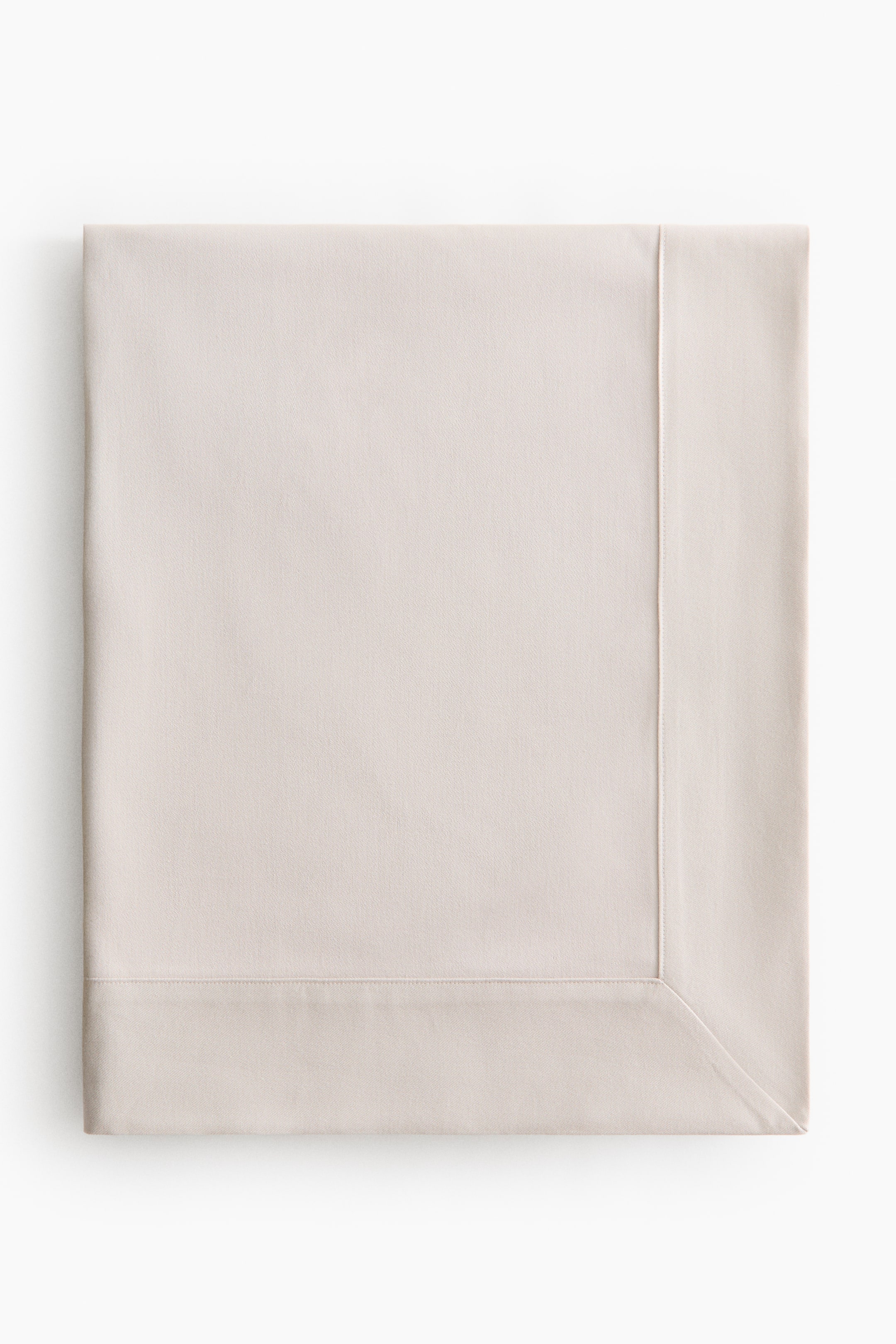 View larger image: A rectangular tablecloth is showing its smooth, light-coloured fabric. It features stitched hems along its edges and precisely mitred corners, viewed from the front.