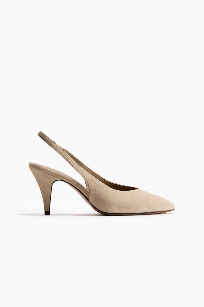 Una décolleté slingback in camoscio beige chiaro mostra il suo profilo laterale, caratterizzata da una punta affusolata, un sottile tacco a spillo e un fine cinturino slingback. - 1