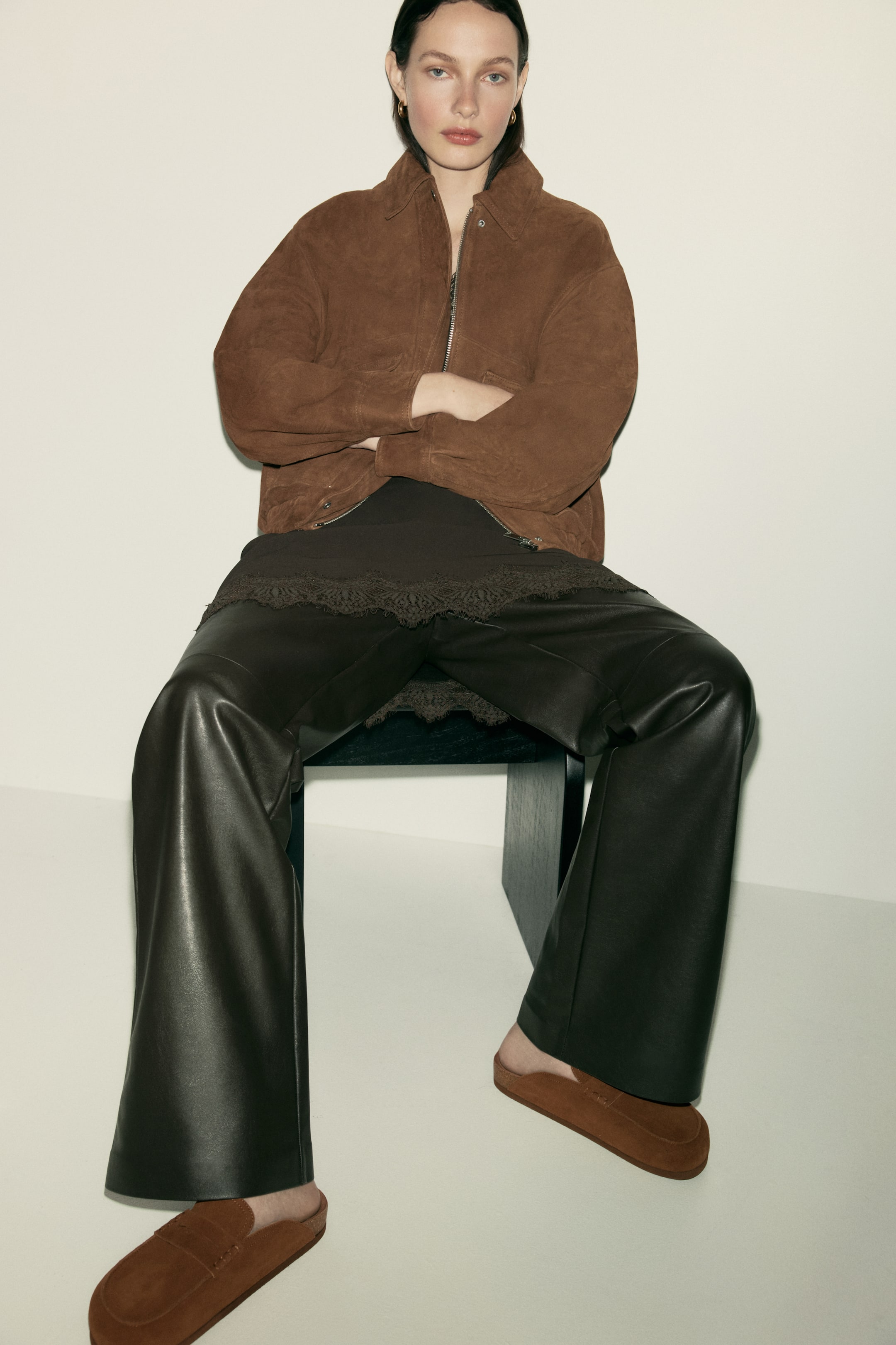 View larger image: "The model is wearing brown suede loafer mules, showcasing a moccasin seam, penny keeper, and oblique toes."