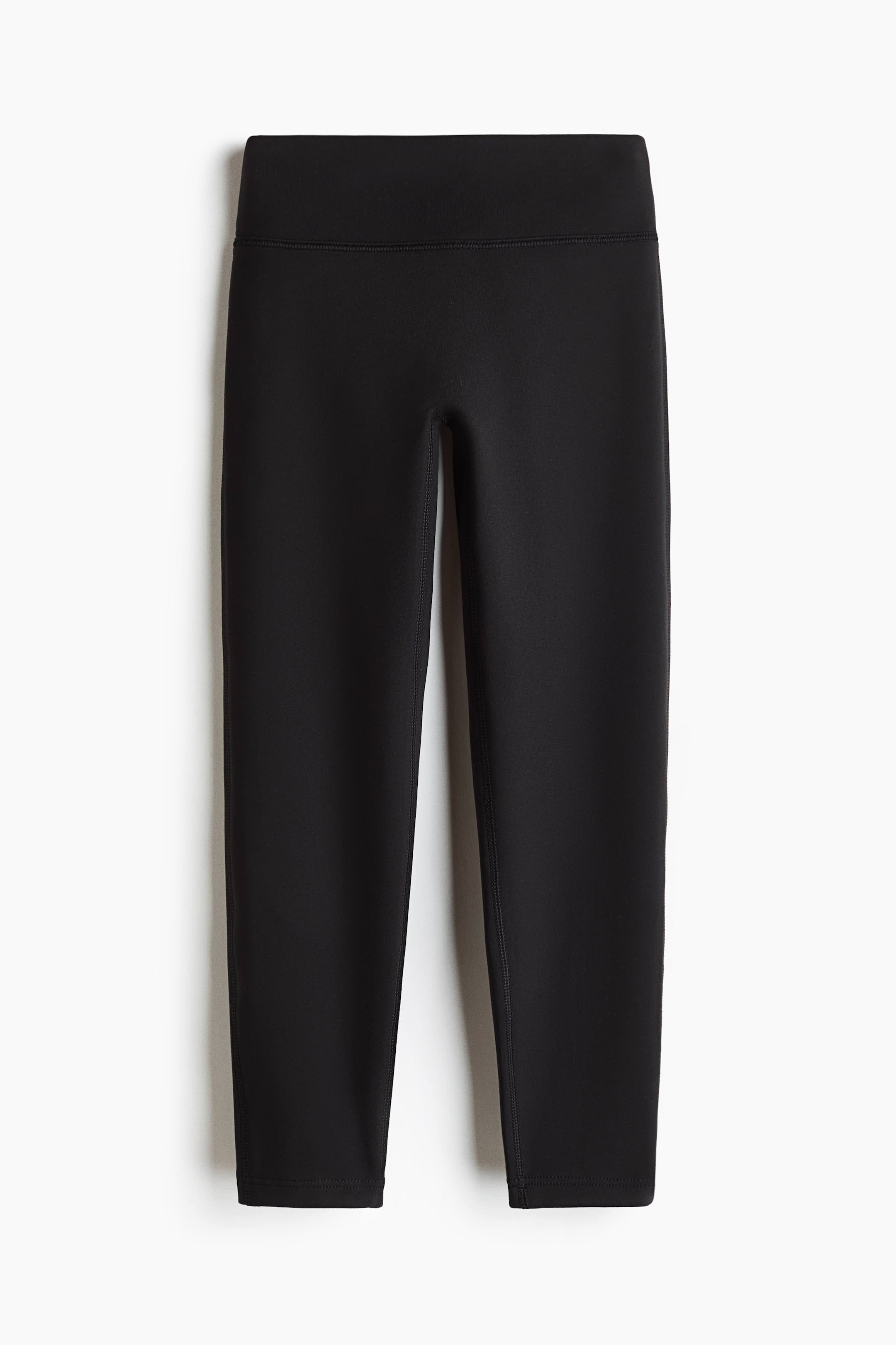 Grotere afbeelding bekijken: Zwarte capri-leggings met een brede, platte tailleband en zichtbare flatlocknaden langs de binnenkant van de benen. De gladde stof toont het kledingstuk van voren.