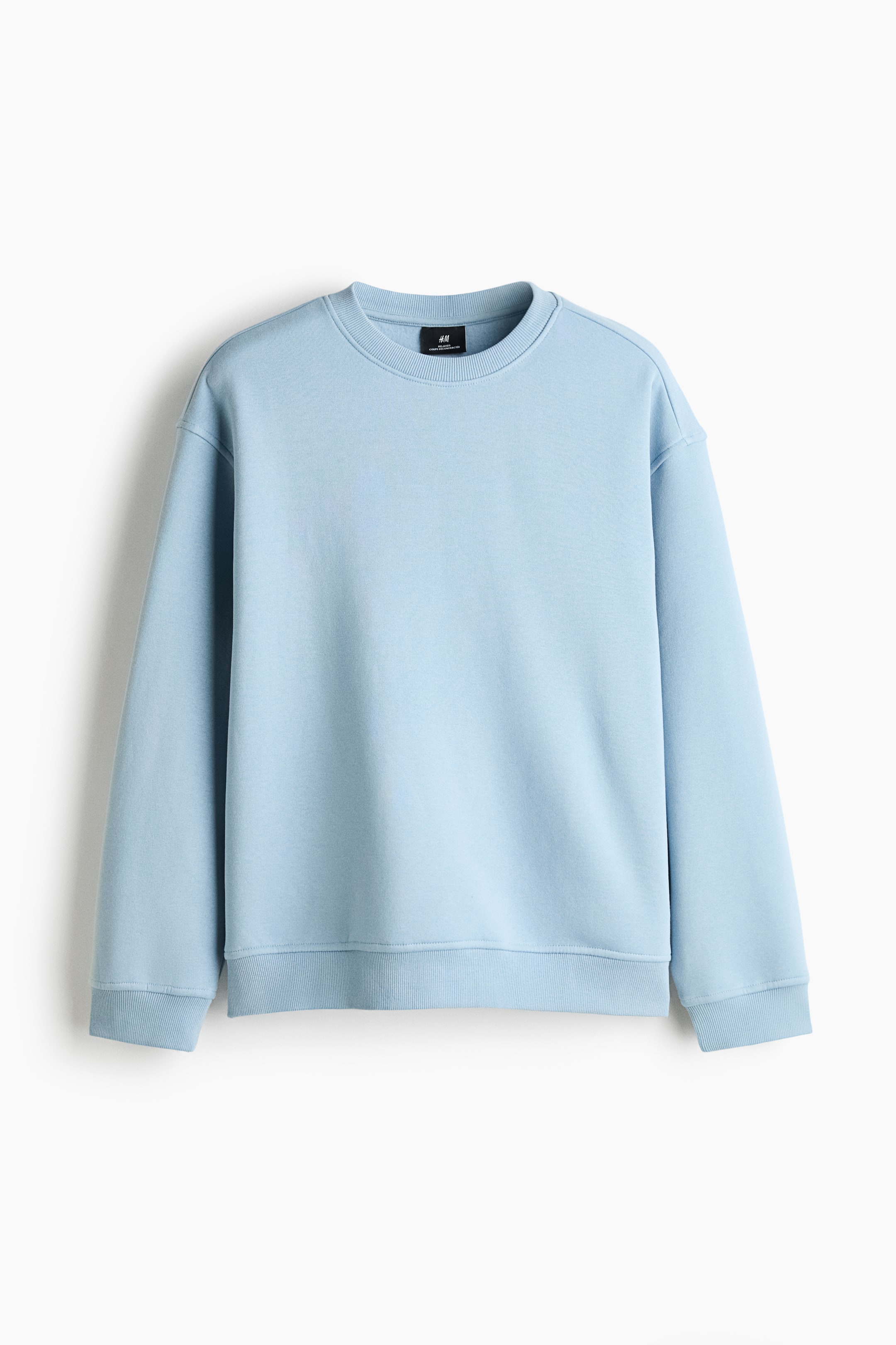 View larger image: A light blue sweatshirt is hanging facing the front, showcasing a loose-fit silhouette with dropped shoulders and long sleeves. The garment features a round, rib-trimmed neckline alongside wide ribbed cuffs and a matching ribbed hem.