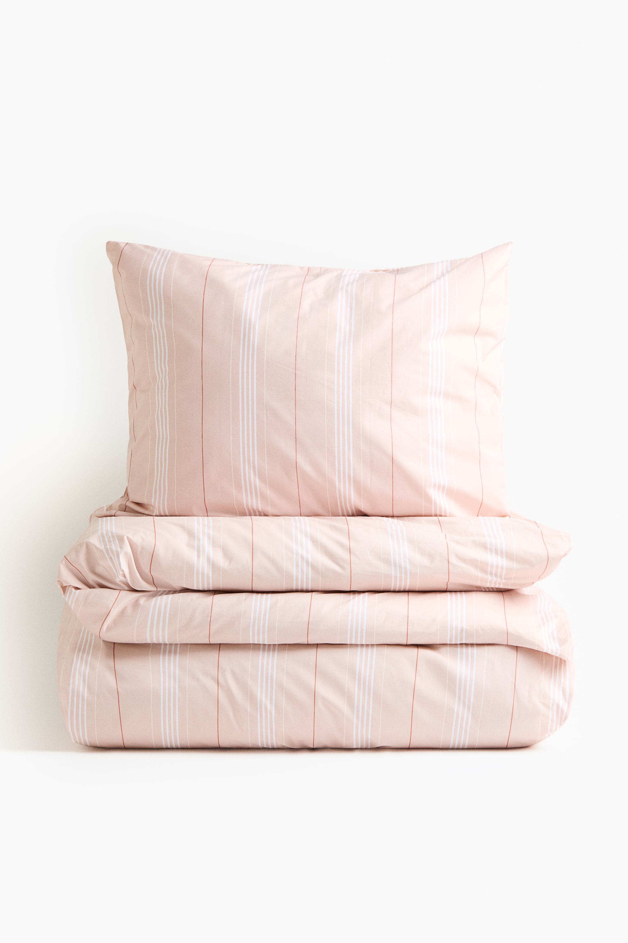 拡大画像を表示: シングルのデュベカバーセットは、ライトピンクの枕カバーと、折りたたまれたデュベカバーを紹介しており、どちらも全体に縦ストライプのパターンが施されています。ストライプは、白、ライトピンク、赤みがかったピンクの線を含み、厚みと色が異なり、生地はマットな仕上がりになっています。