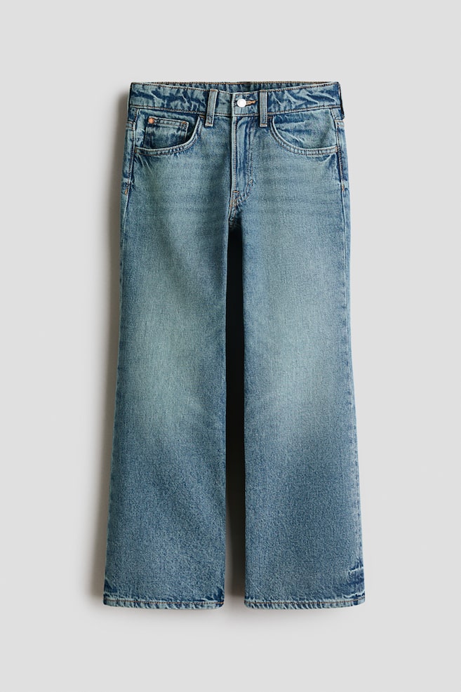 Les jeans à 5 poches sont présentés en vue de face, arborant un denim en coton bleu clair à moyen. Ils sont conçus avec une coupe ample au niveau des hanches, des cuisses et des jambes, une fermeture éclair avec bouton à la taille, et des jambes larges. - 1