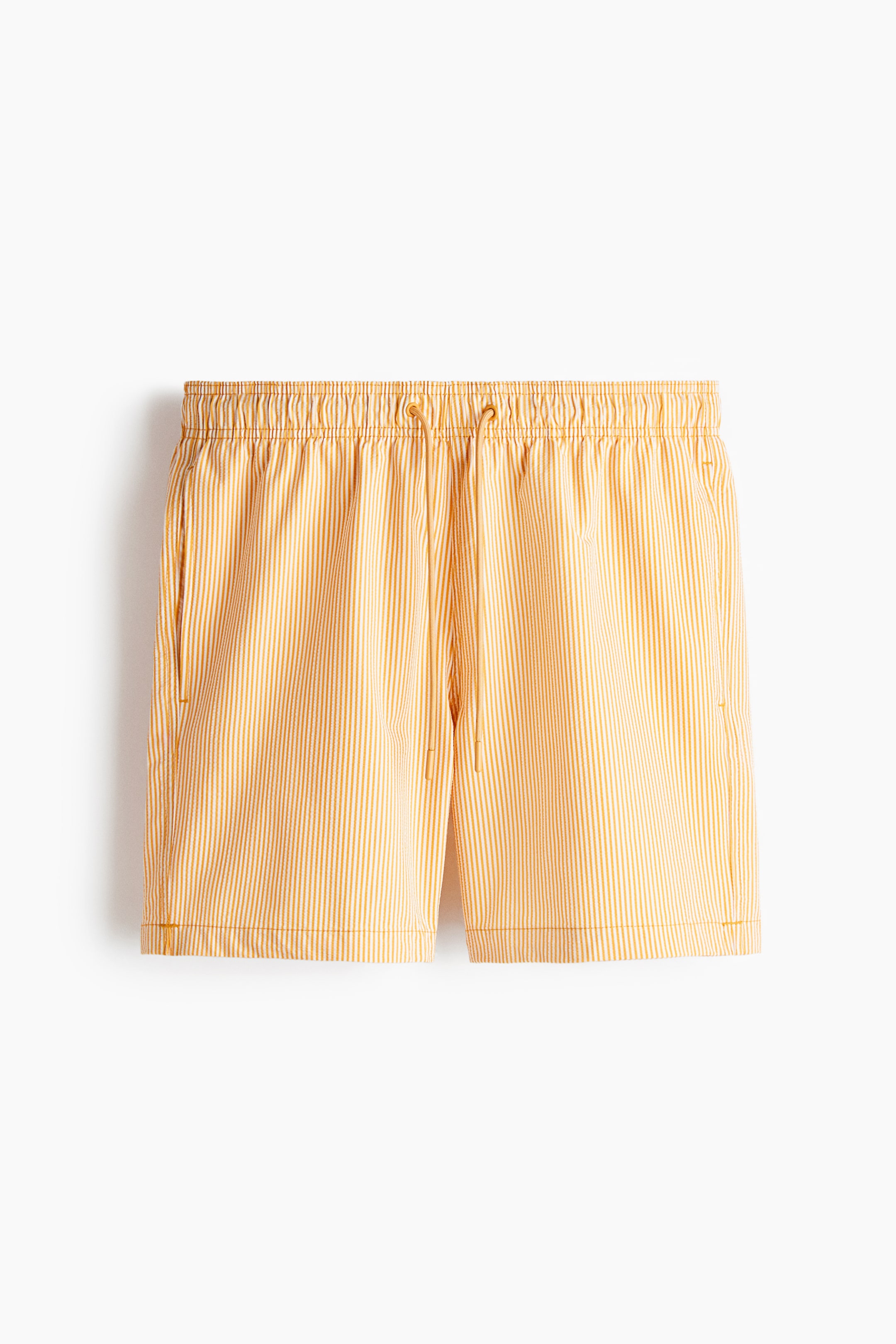 View larger image: The shorts feature light orange and white vertical stripes and have an elastic waistband with a matching light orange drawstring and toggles. They also include side pockets and a small embroidered detail on the lower right leg.