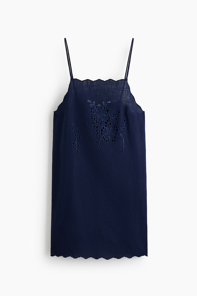 Un haut à bretelles fines de couleur bleu marine présente des bretelles spaghetti et un décolleté festonné. L'avant du haut est orné d'une broderie florale ajourée, et l'ourlet du bas est également festonné. - 1