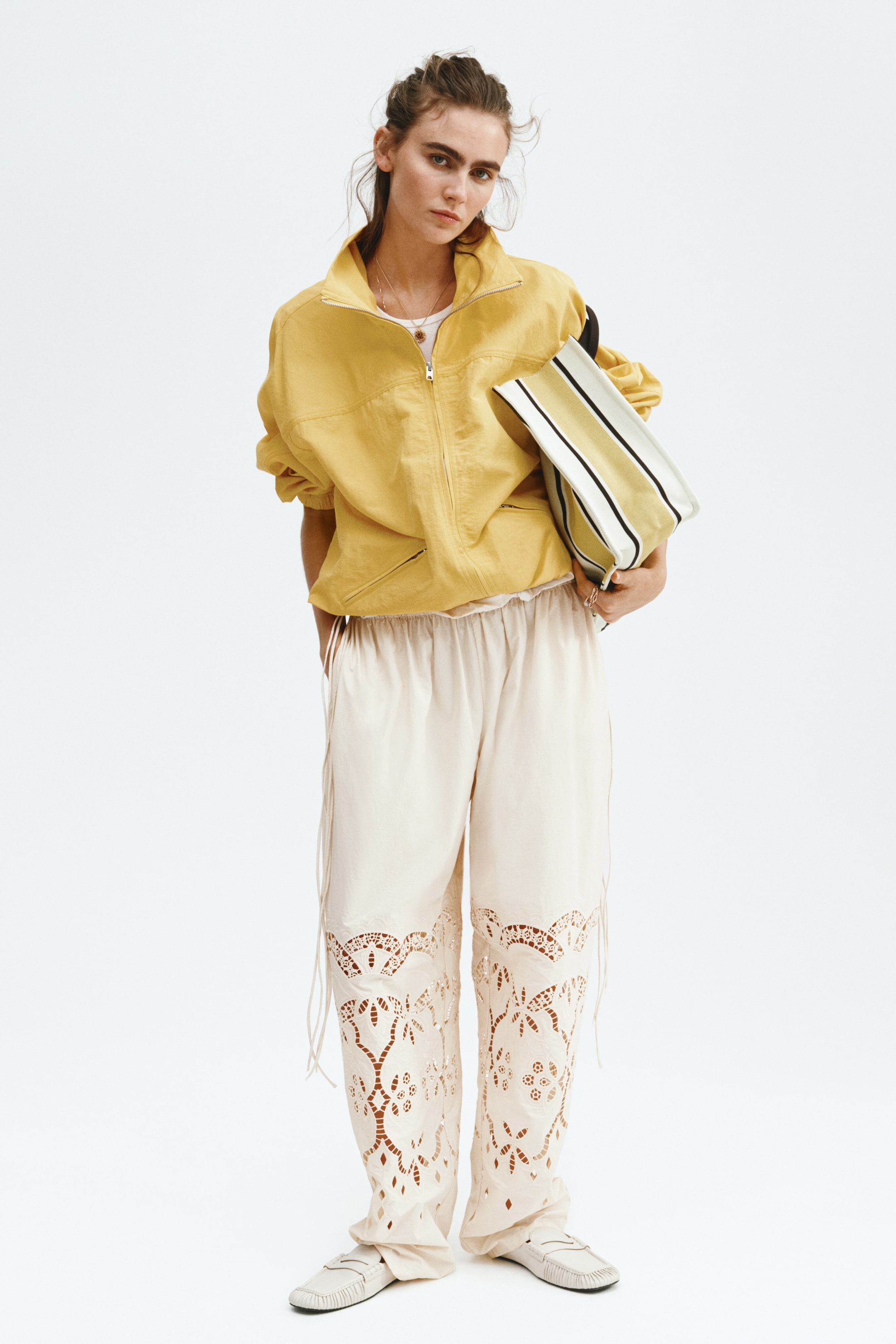 Grotere afbeelding bekijken: Crèmekleurige wijde broek met een elastische, geplooide tailleband, ingewikkelde uitsneden op de onderbenen en dunne trekkoorden langs de zijkanten.