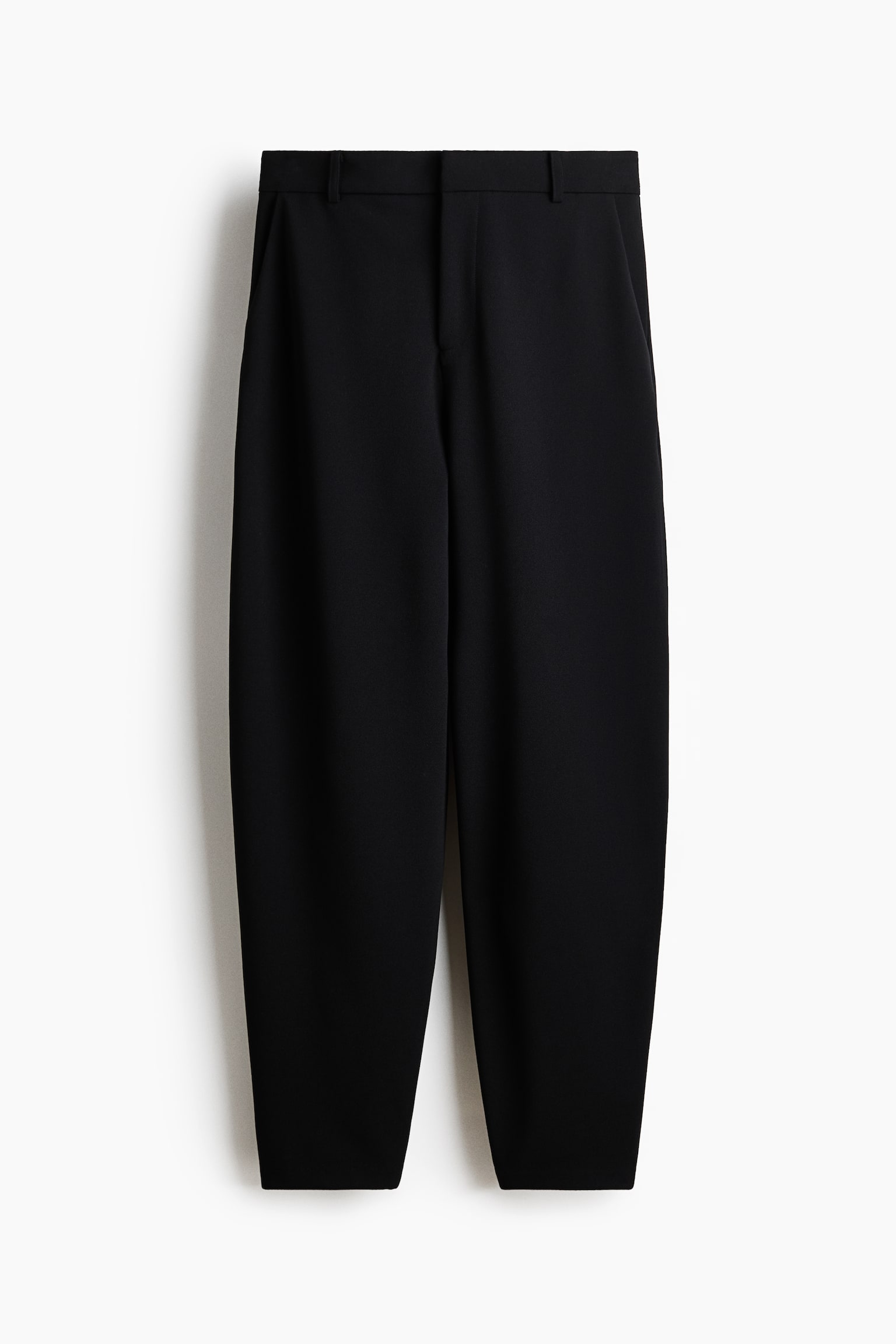 Black trousers made from a heavy jersey material are showcased in a front view, highlighting a high, elasticated waist with a zip fly and a concealed hook-and-bar fastener. They feature diagonal side pockets and barrel legs. - 1