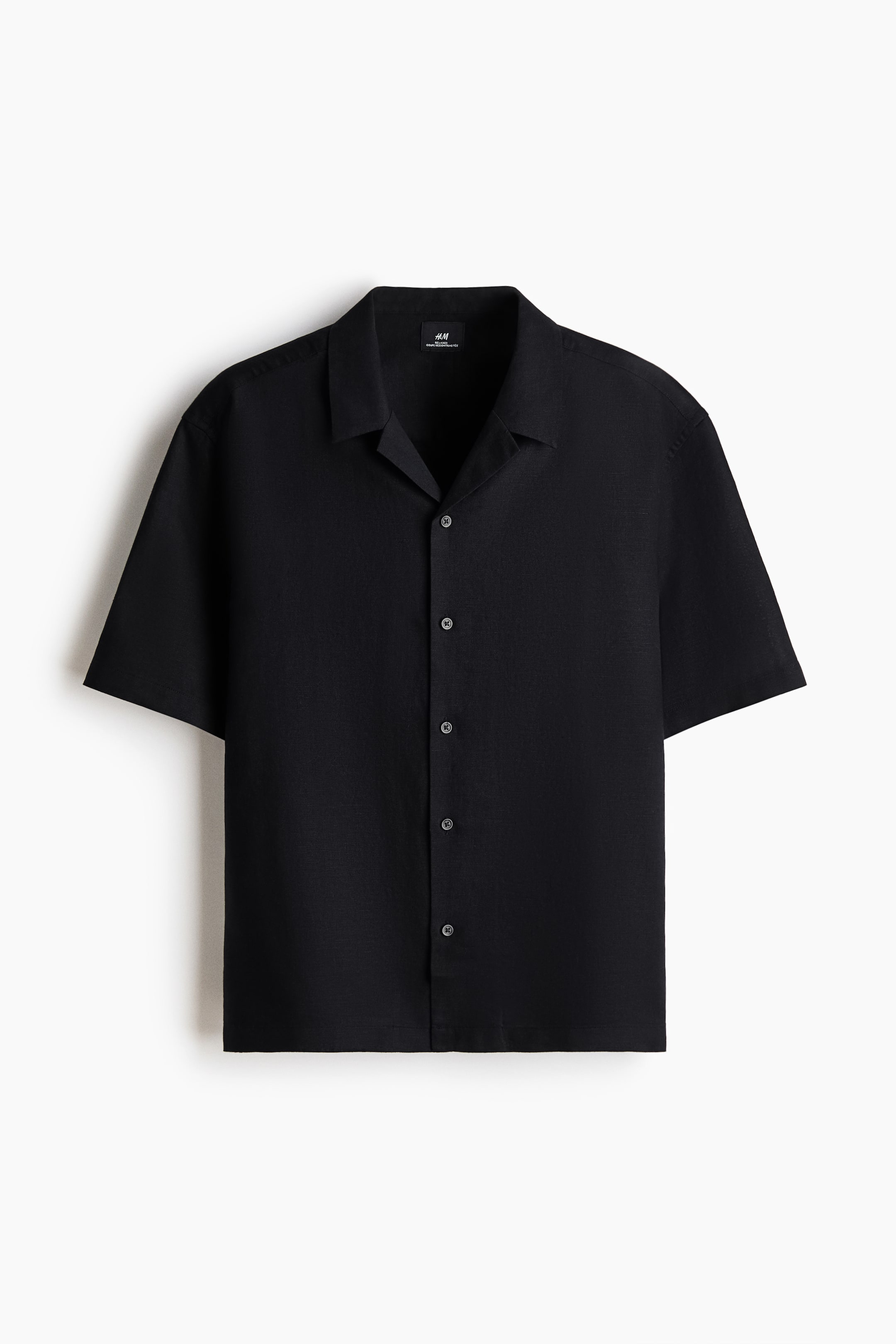 View larger image: A black short-sleeved shirt is facing front, and it features a camp collar and a full button-front closure with dark buttons. The shirt displays a slightly textured fabric.