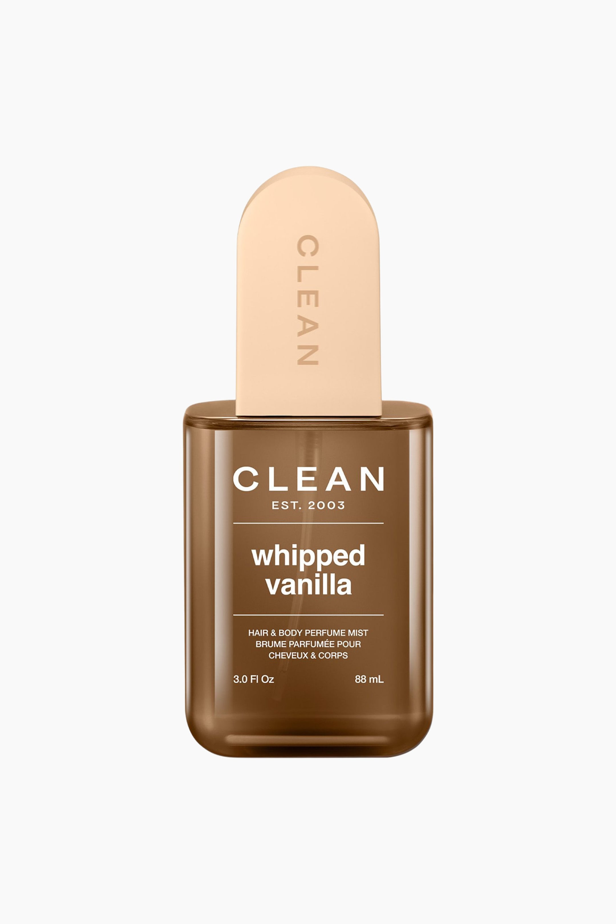 Se større billede: "The Clean Whipped Vanilla Hair & Body Perfume Mist vises forfra, med en gennemsigtig brun rektangulær flaske med afrundede kanter og en lys beige, afrundet rektangulær hætte, der viser 'CLEAN' vertikalt. Flasken er mærket med 'CLEAN EST. 2003 whipped vanilla HAIR & BODY PERFUME MIST 3.0 Fl Oz 88 mL' i hvid tekst."