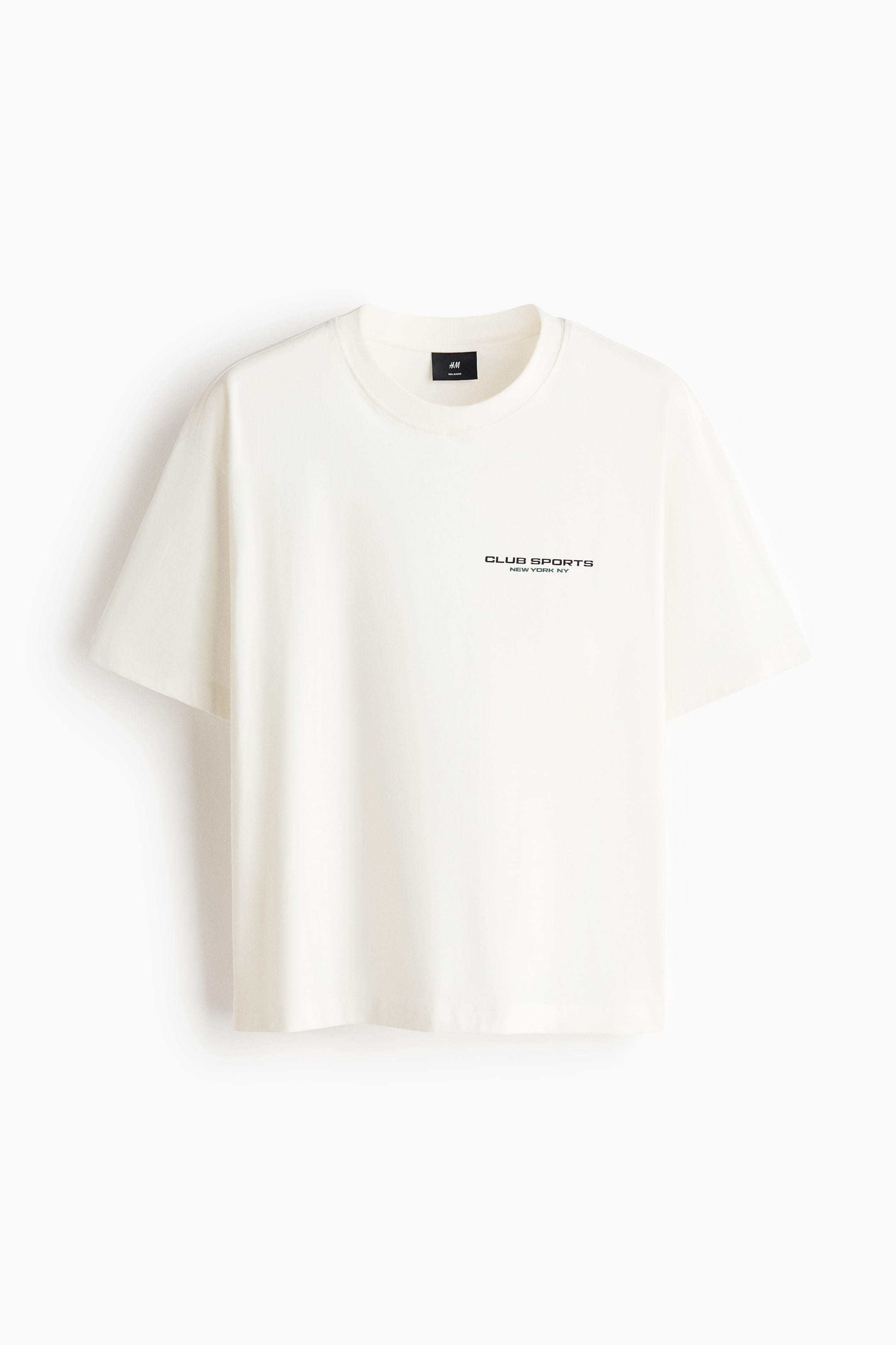 Grotere afbeelding bekijken: Een crèmekleurig T-shirt wordt getoond, met een geribde ronde hals en korte mouwen, met "CLUB SPORTS NEW YORK, NY" in zwarte letters op de voorkant gedrukt.