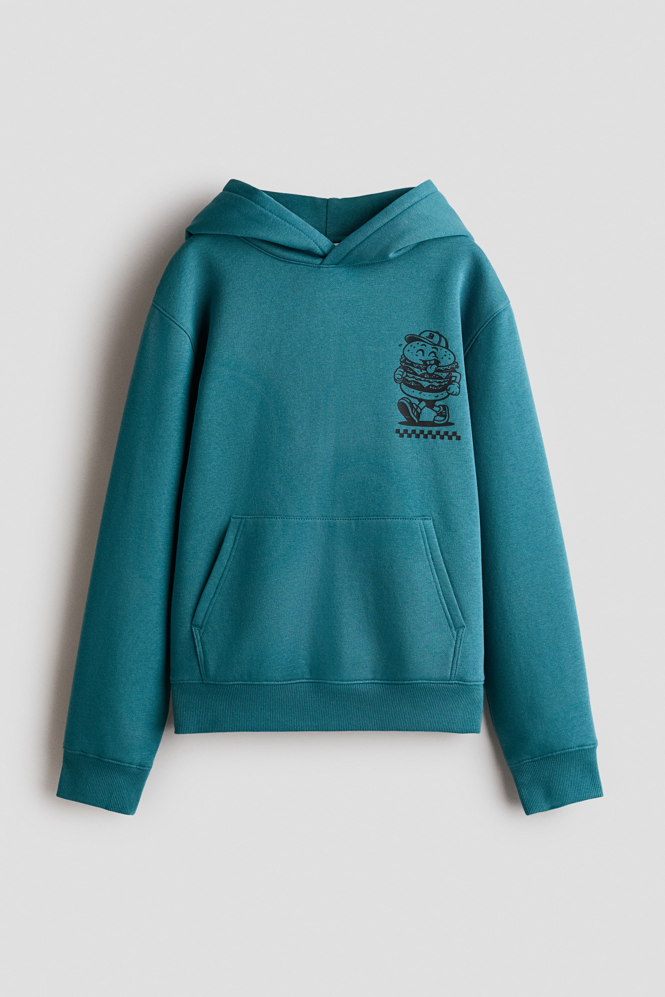 Grösseres Bild ansehen: Ein petrolfarbener Hoodie ist von vorn zu sehen, mit einer gefütterten Kapuze und Wickelkragen, überschnittenen Schultern und einer vorderen Kängurutasche. Das Kleidungsstück zeigt auf der linken Brust eine kleine schwarze Grafik eines Comic-Hamburger-Charakters und ist mit geripptem Saum und gerippten Bündchen versehen.