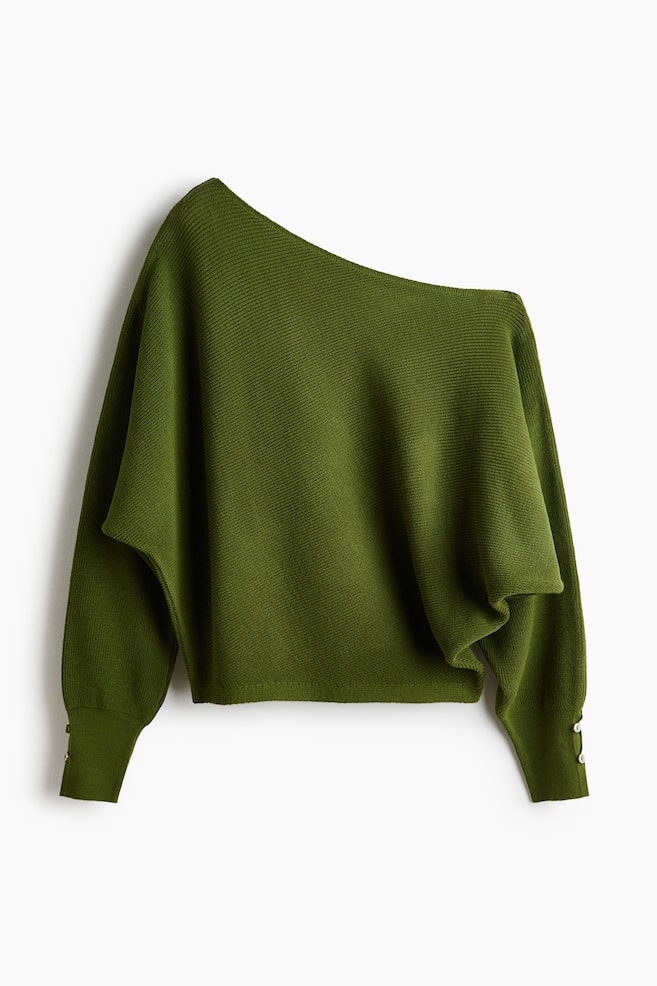 Un jersey de punto verde oliva visto de frente, con un escote asimétrico de un solo hombro y un cuerpo holgado con caÃda. El jersey presenta mangas largas con puños acanalados extendidos, detallados con pequeños botones en las muñecas. - 1