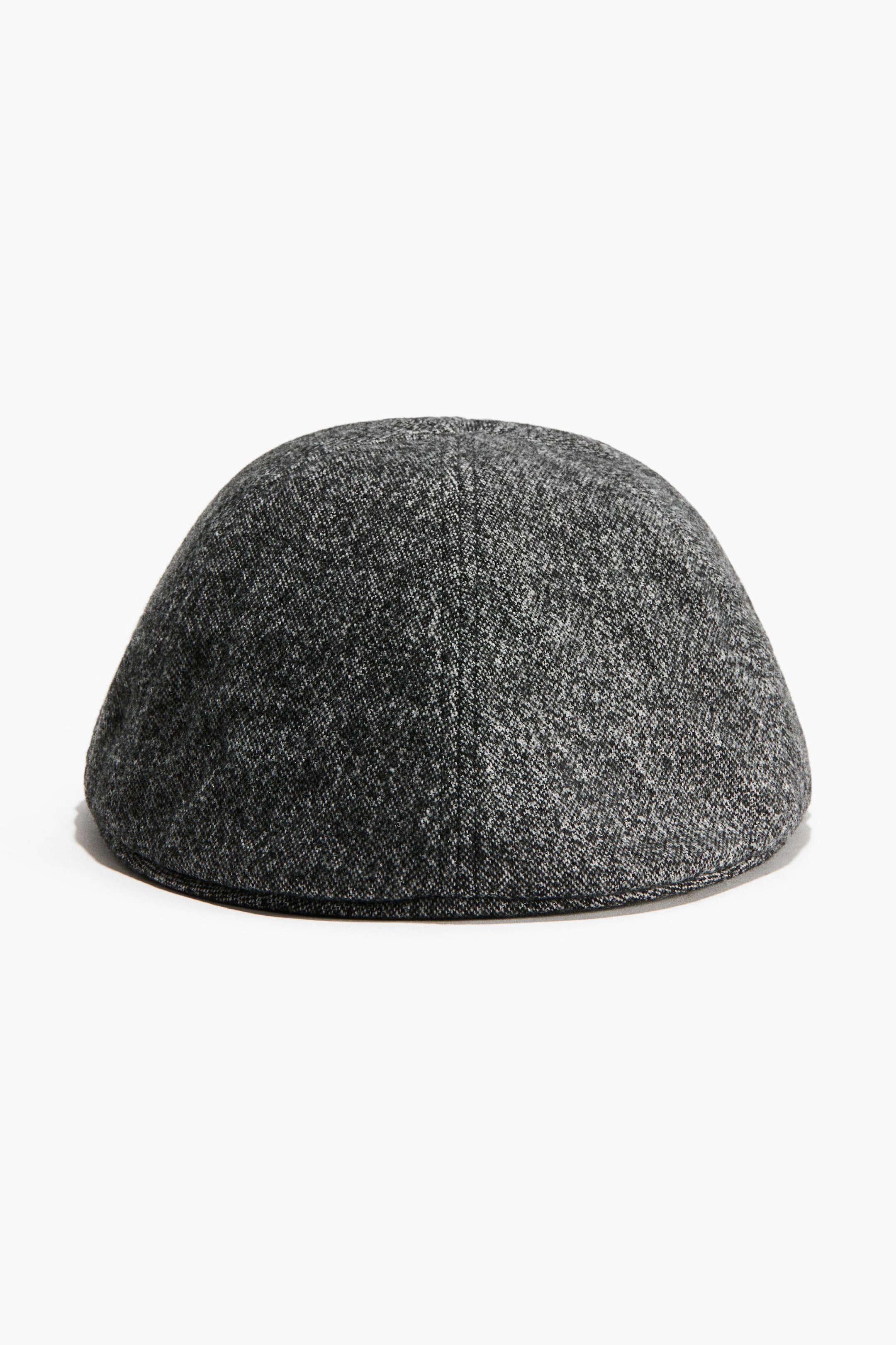 View larger image: A flat cap is displaying a rounded, dome-shaped crown in a speckled black and grey textured weave, shown from the rear with a vertical centre seam.