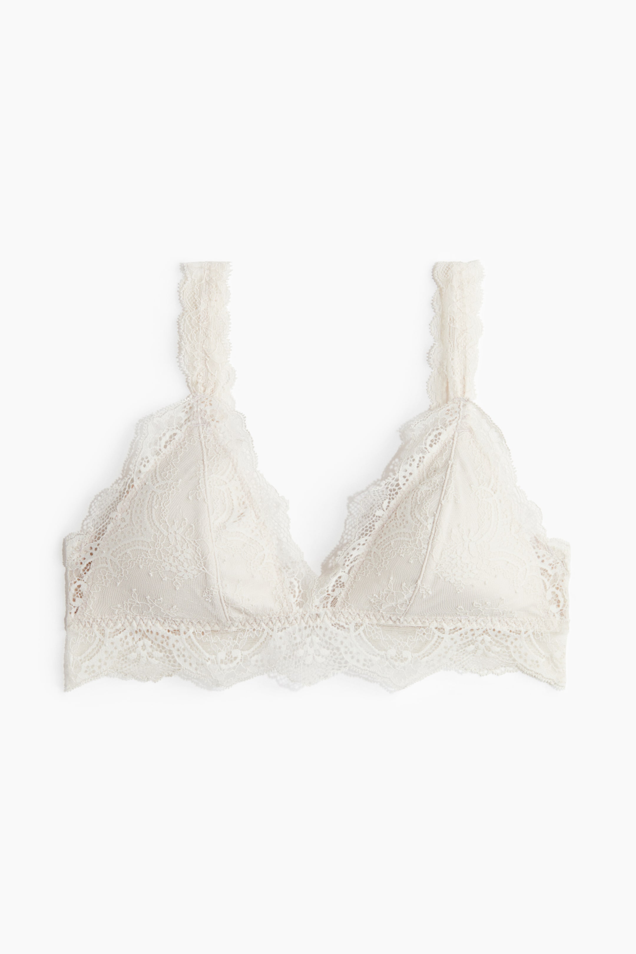 View larger image: A front view of an off-white bralette is displaying soft triangle cups, each with a smooth lining beneath a delicate lace overlay. The bralette is featuring a wide lace underband and thin lace straps, all trimmed with scalloped edges.