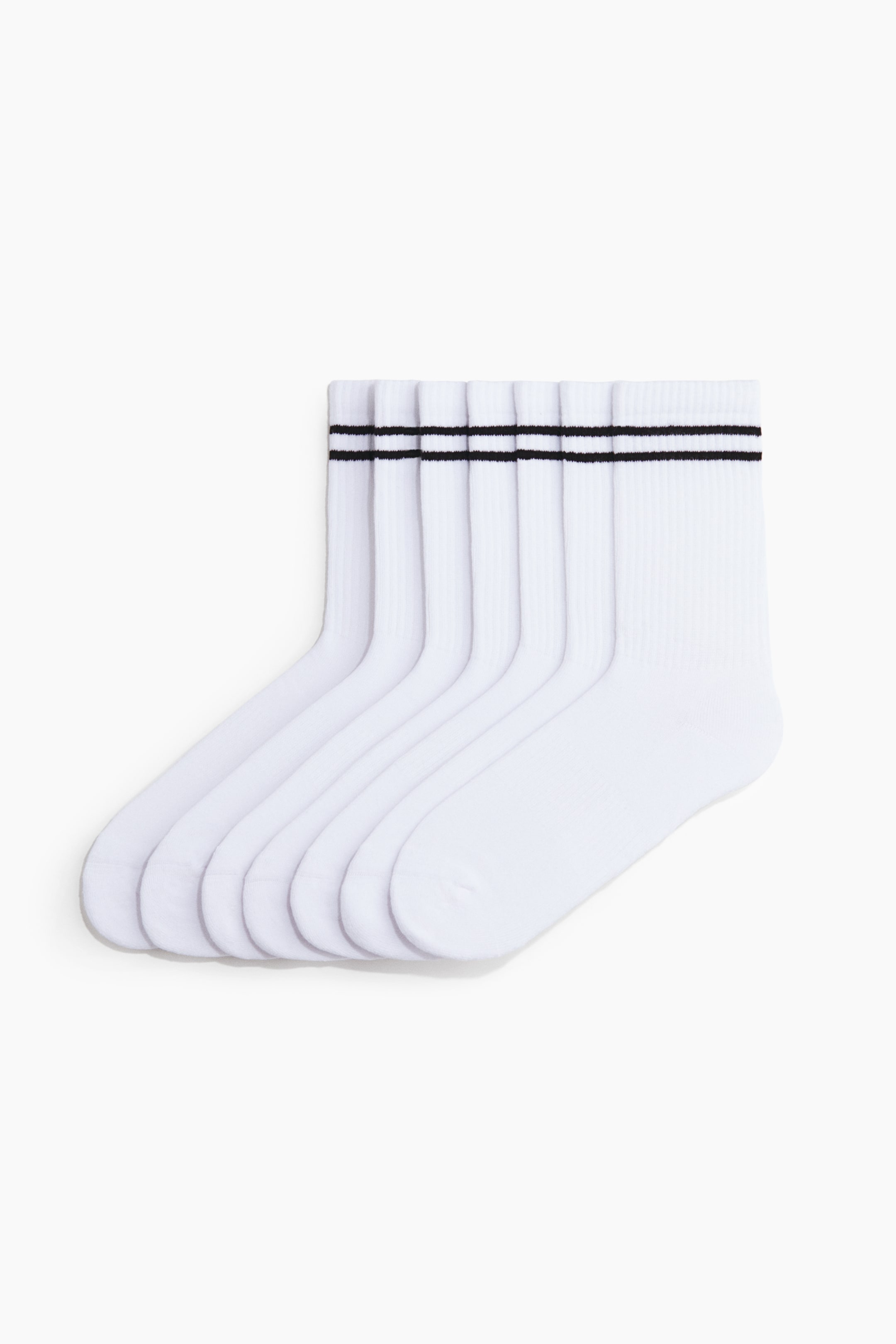 Ver imagem maior: Seis meias brancas de cano alto estão empilhadas e desdobram-se para a direita, exibindo os seus perfis laterais. Cada meia apresenta um punho canelado com duas riscas pretas paralelas próximas do topo.