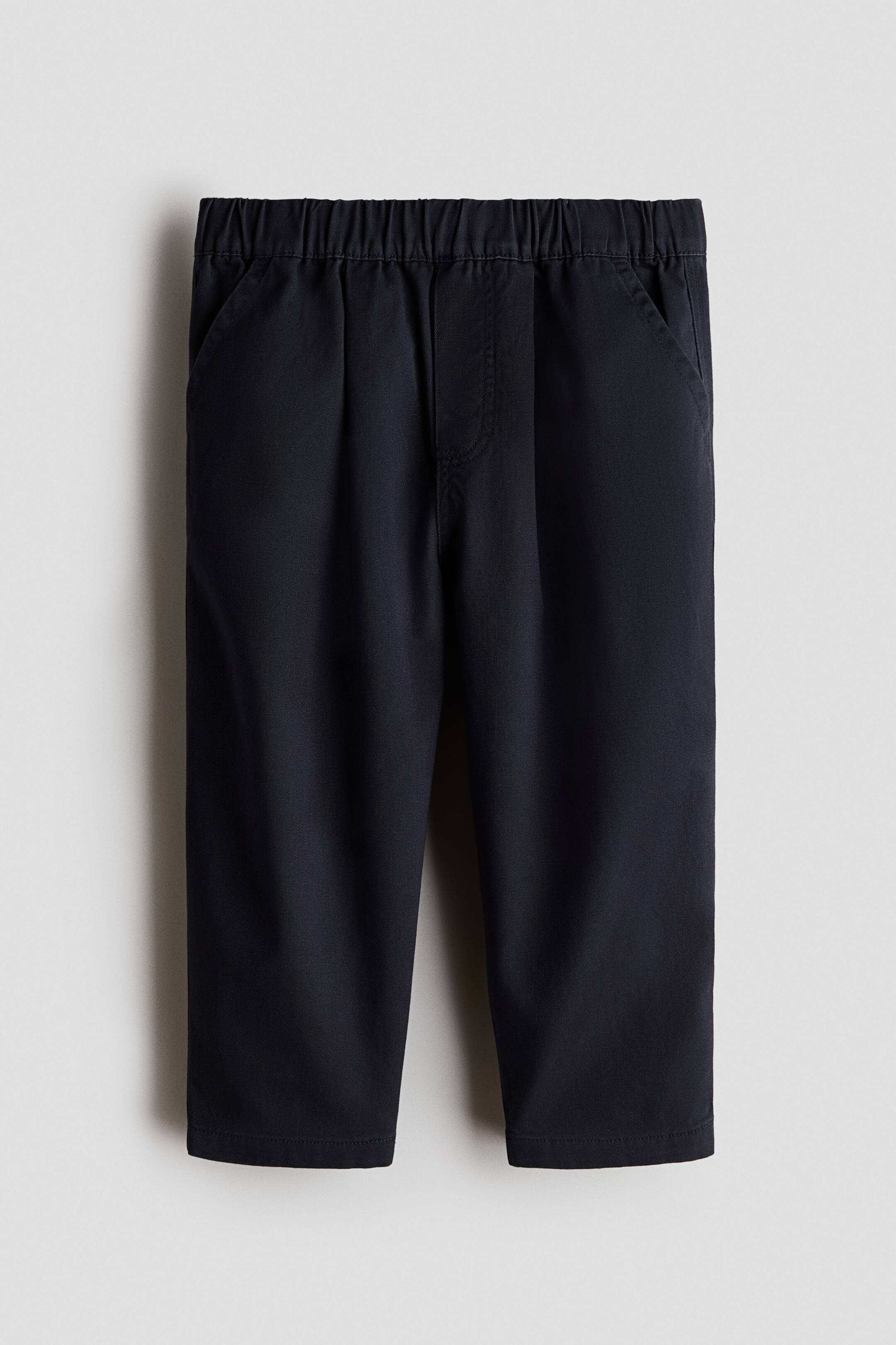 Voir une image plus grande: Un pantalon bleu marine est présenté de face, avec une taille élastiquée et des poches en biais sur les côtés. Chaque jambe présente un pli souple et un ourlet net.