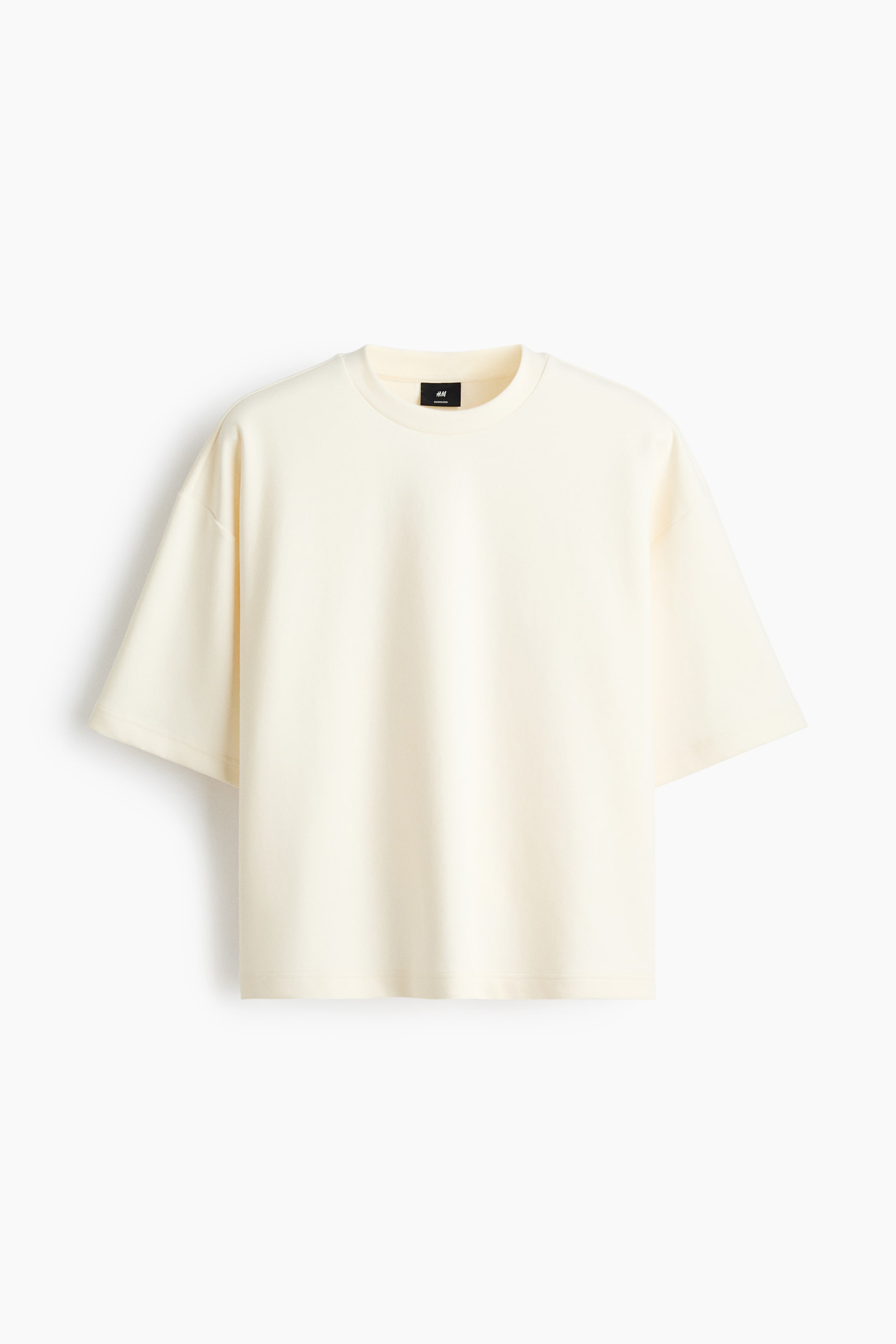 View larger image: The cream t-shirt is shown from the front, highlighting a ribbed round neckline with a visible black tag inside, wide short sleeves, and a relaxed fit.