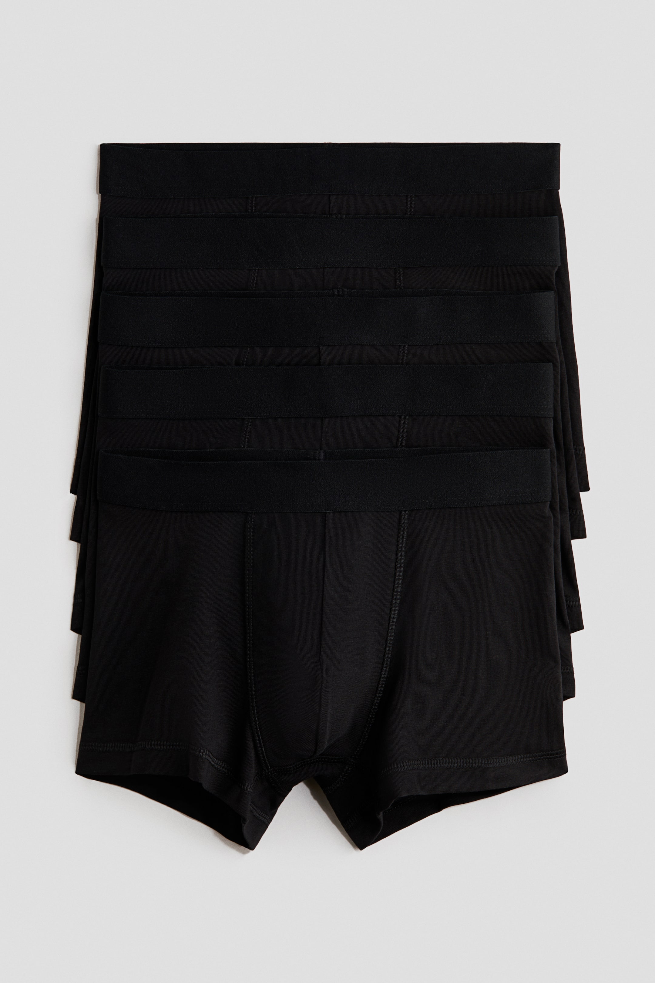 Voir une image plus grande: Une pile de boxers noirs est posée à plat et orientée vers l'avant. Chaque paire est dotée d'une ceinture élastique noire unie, de jambes courtes, et d'un détail de couture ton sur ton sur la poche avant et les coutures.