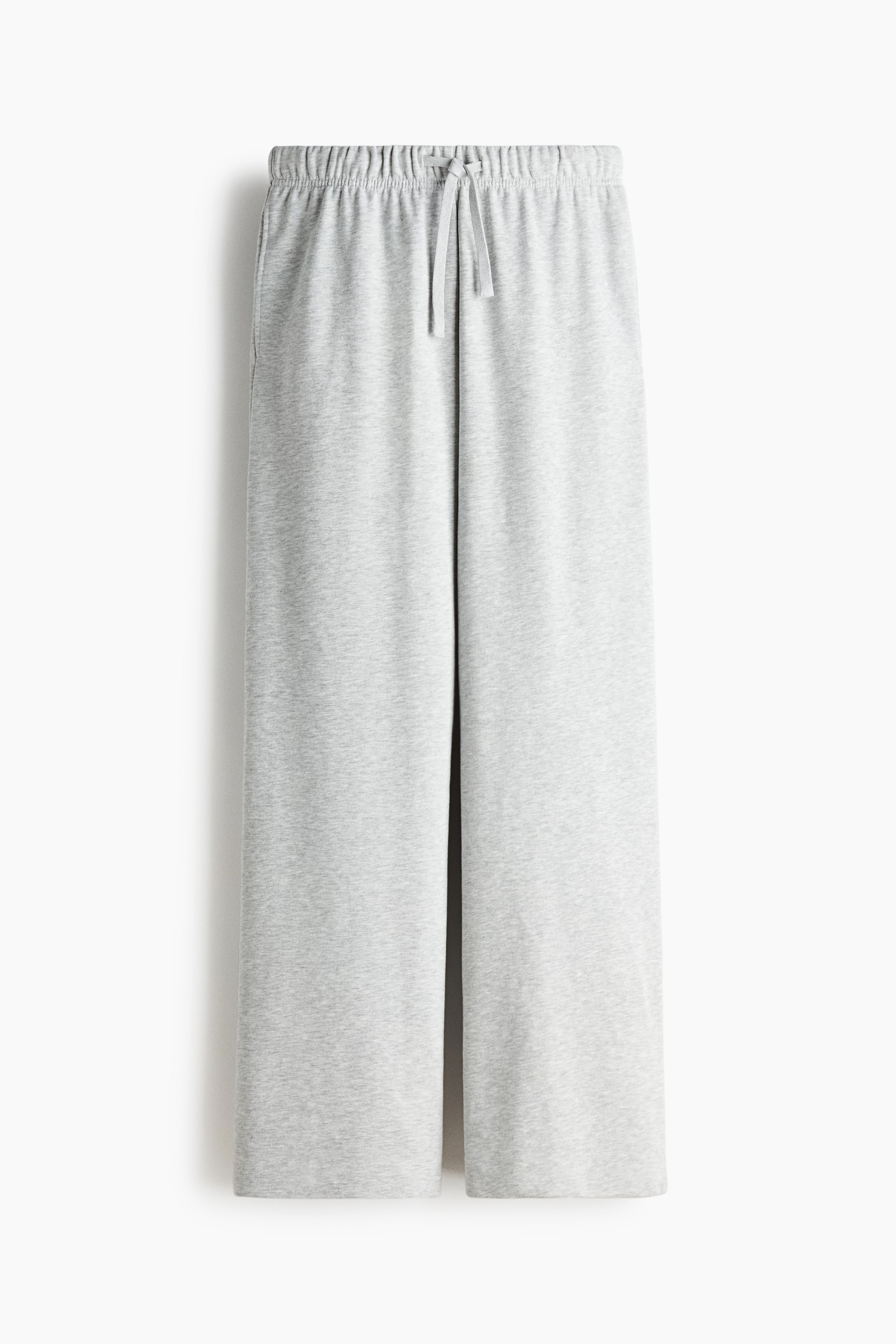 Agrandir l'image: Des pantalons de survêtement gris clair sont présentés de face, avec une taille élastiquée et un cordon de serrage noué. Ces pantalons présentent une coupe large et un ourlet simple.