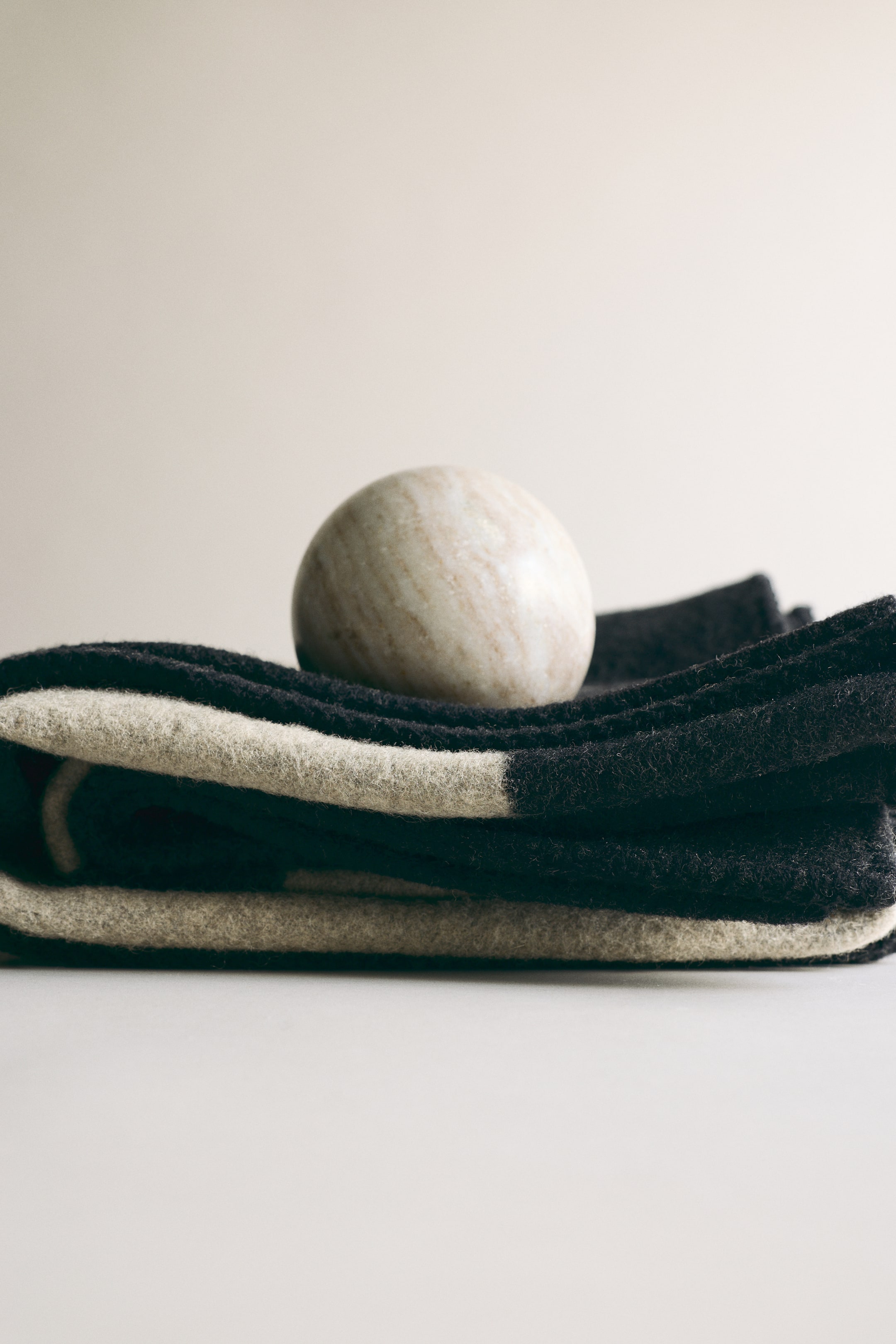 הצגת תמונה גדולה יותר: שמיכה עבה מקופלת, המציגה דוגמת ג'קארד בולטת של פסים כהים ובהירים לסירוגין על אריג בתערובת צמר.