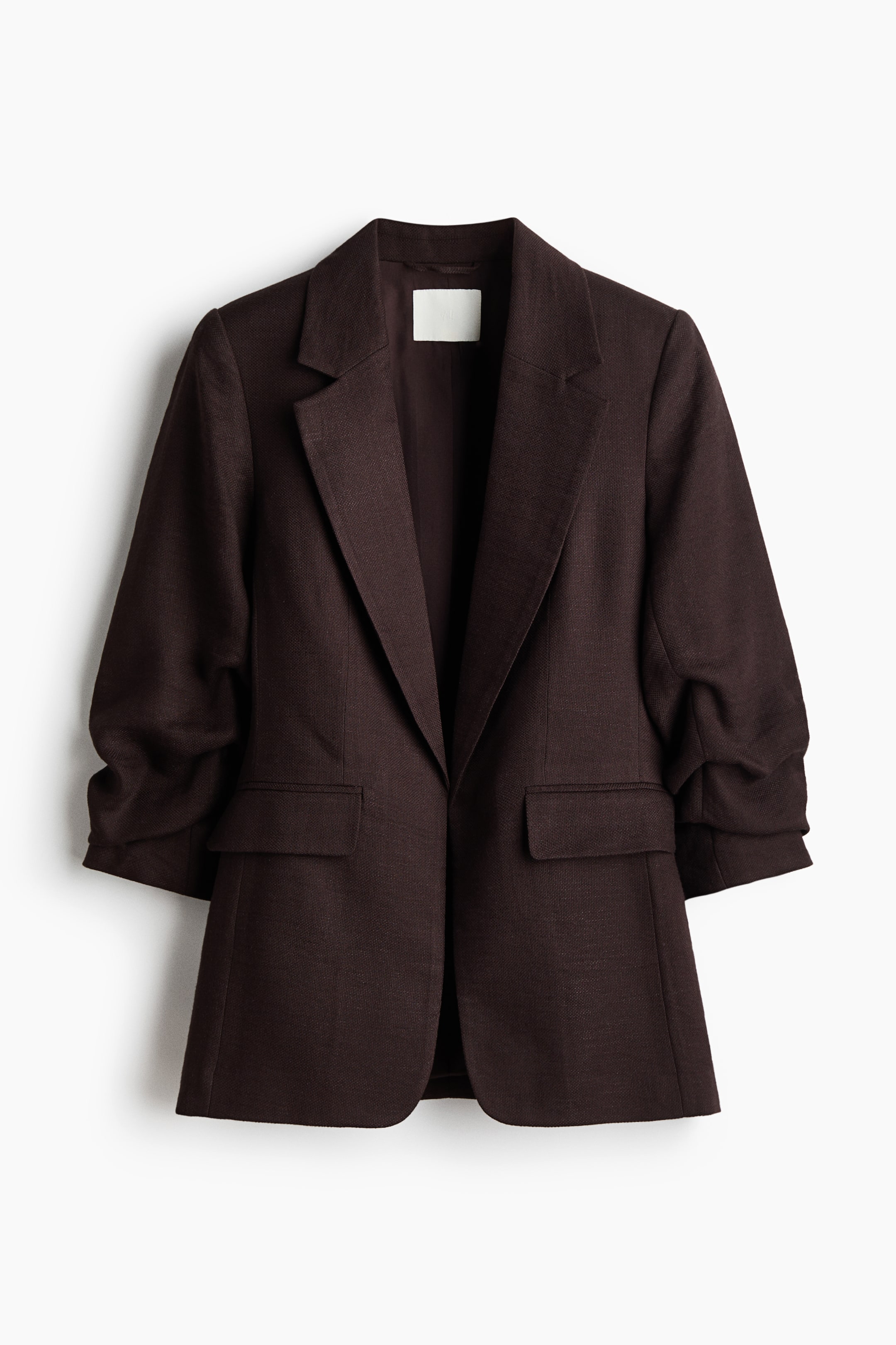 View larger image: A tailored dark brown blazer crafted from woven fabric is showcased from the front. It boasts notch lapels, gathered 3/4-length sleeves, and flap front pockets, with an open front design and no fasteners.