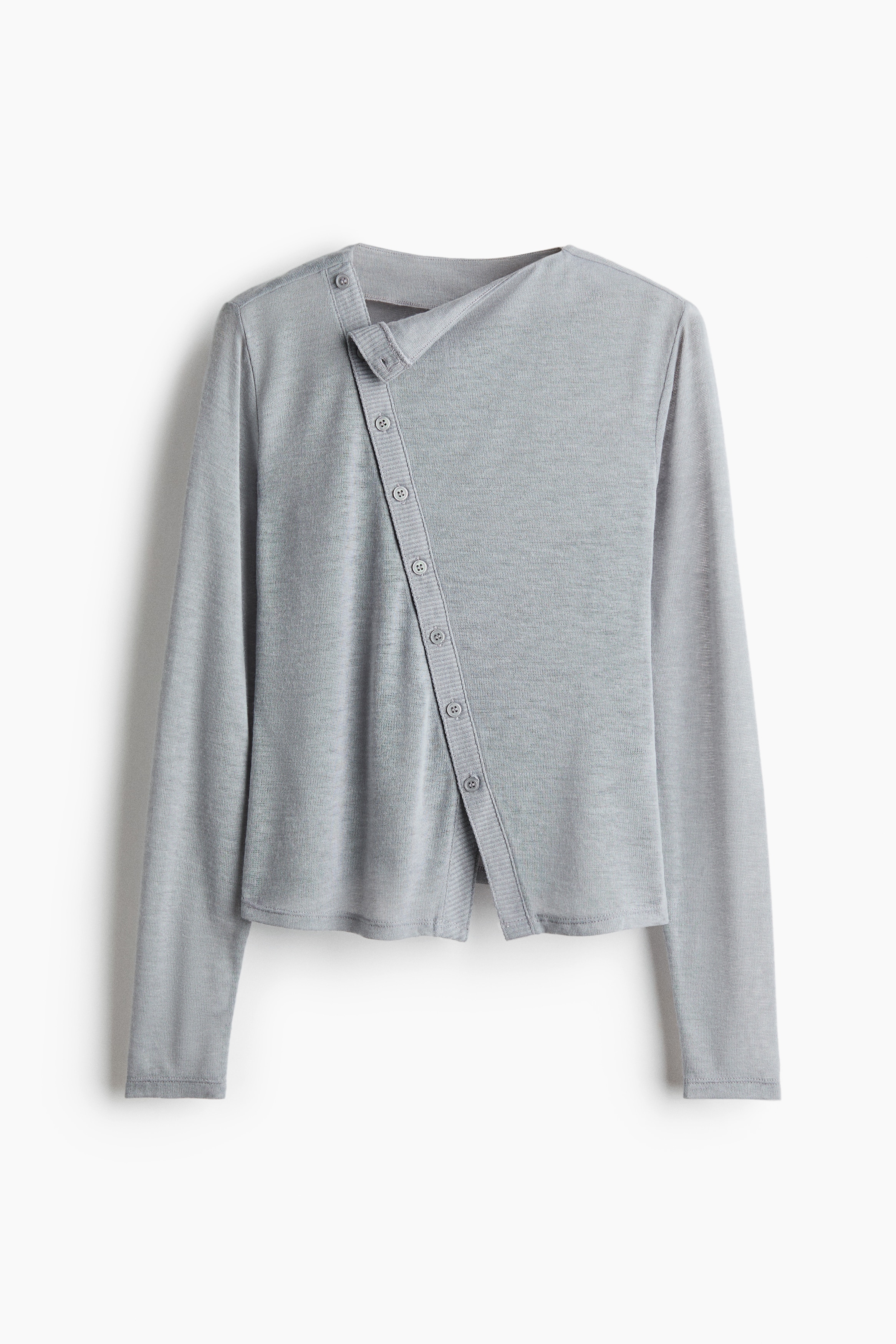 A light grey, semi-sheer, fine-knit top is worn by the model, featuring a high neckline, long sleeves, and a diagonal ribbed button placket running down the front. The top is styled with light-wash distressed blue jeans.
