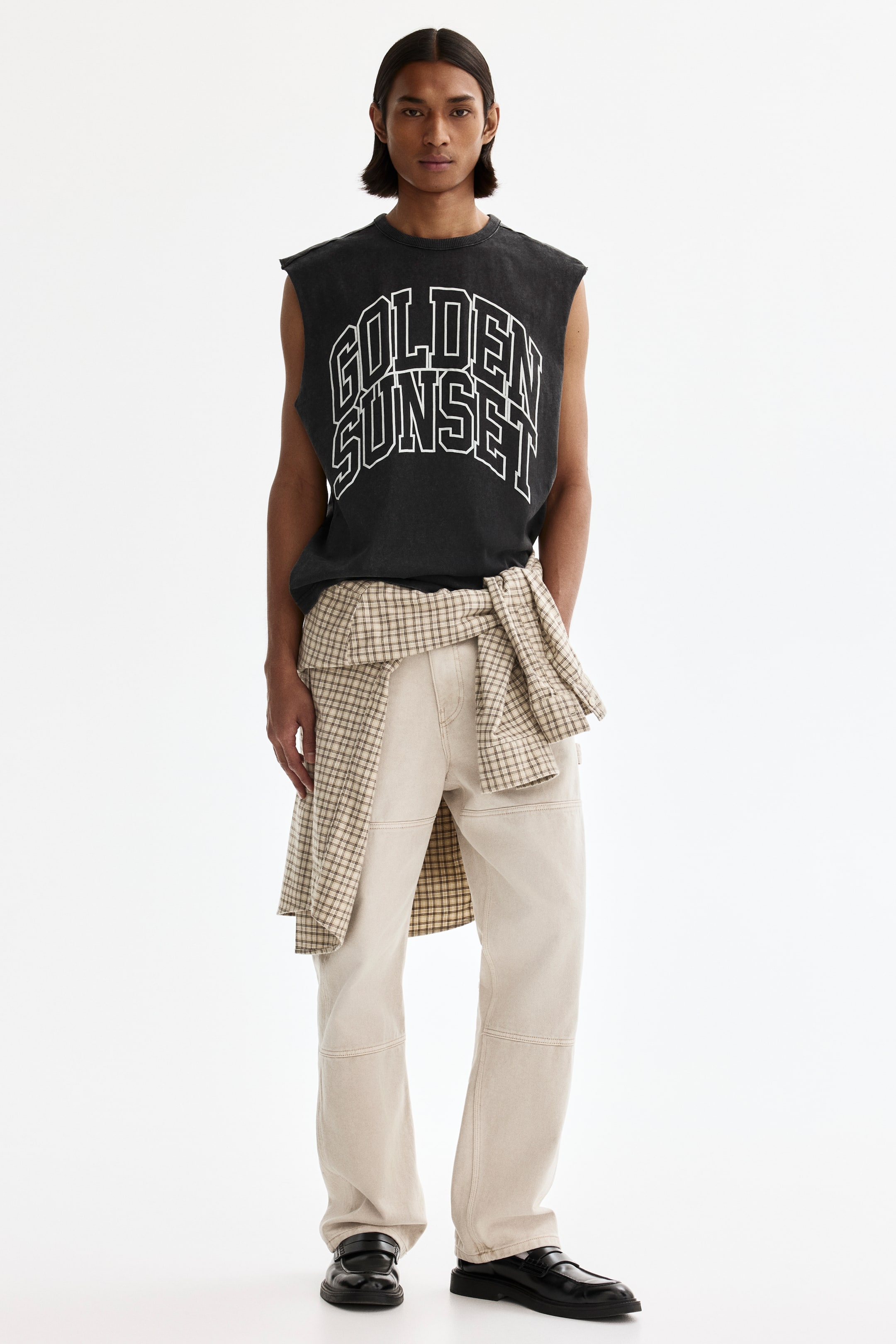 View larger image: Dark gray sleeveless T-shirt displaying "GOLDEN SUNSET" in white-outlined block letters across the chest, with a crew neck and raw-edge armholes.