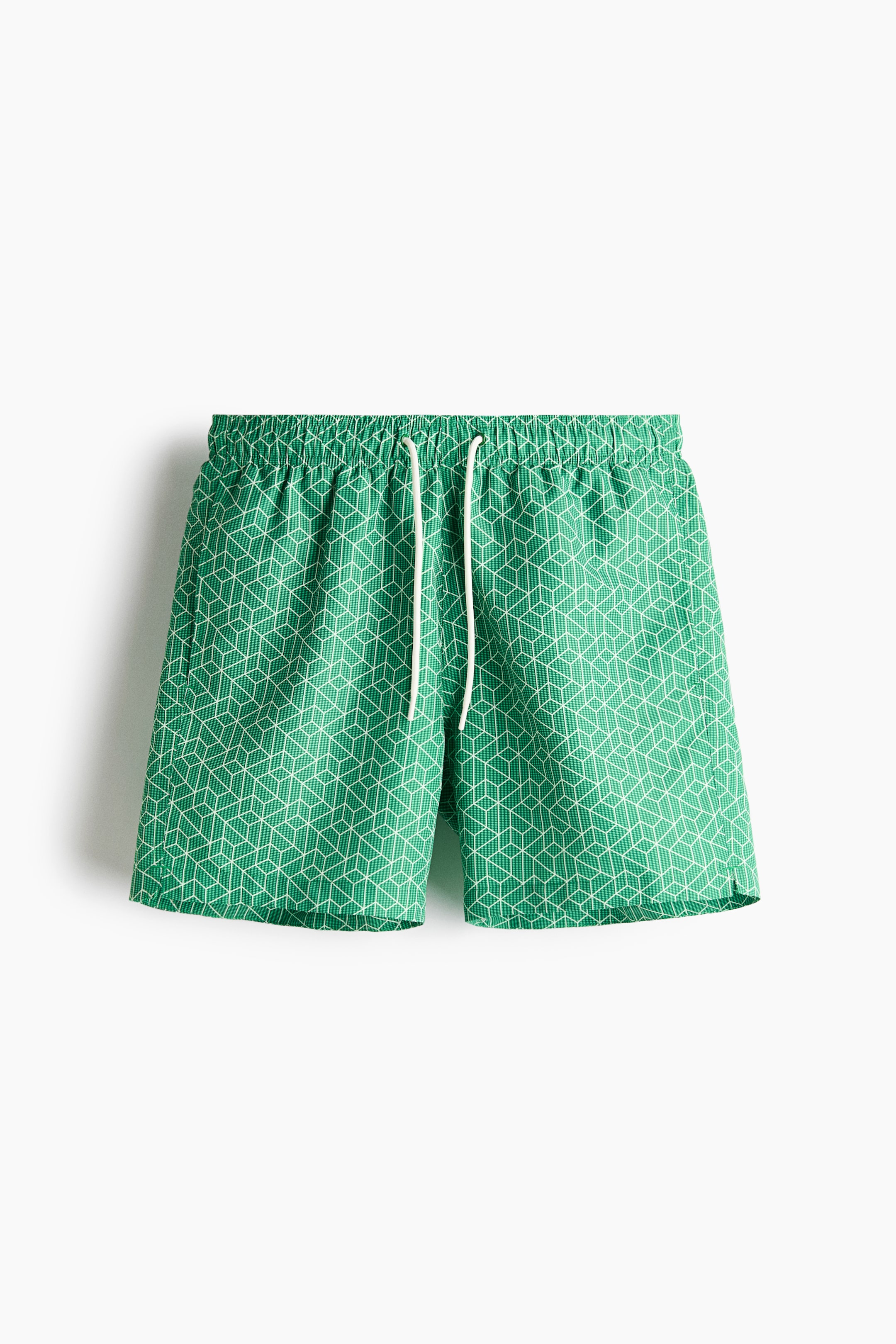 View larger image: Green swim shorts with a white geometric pattern are shown from the front. They feature a covered elastic waistband, a white drawstring, and small side slits at the hem.